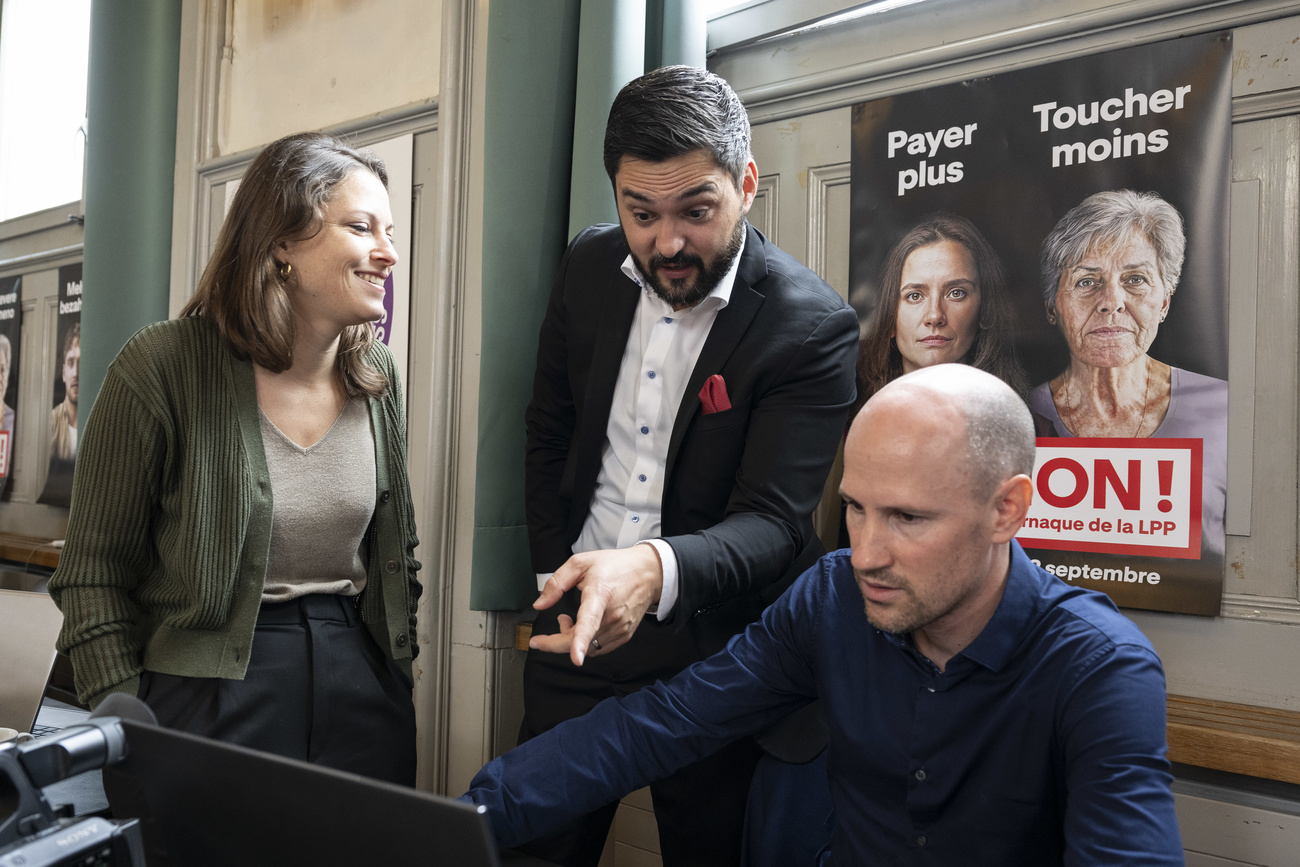 Deux hommes et une femme devant une affiche.