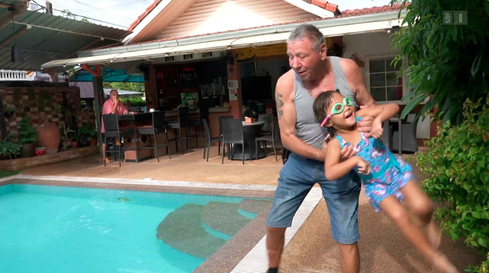 Un retraité avec sa fille au bord d'une piscine