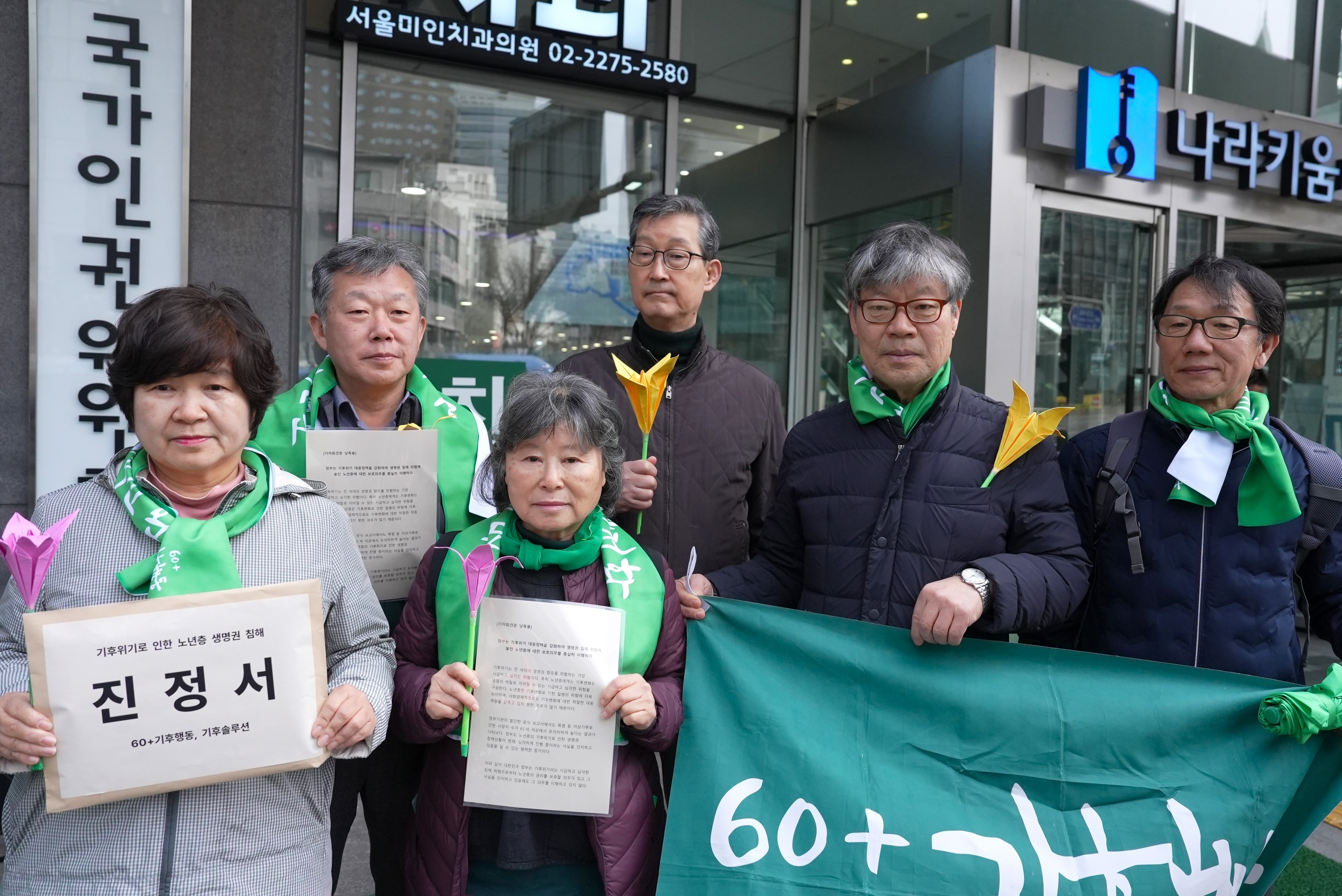 un gruppo di persone perlopiù anziane tiene dei cartelloni con delle scritte in coreano