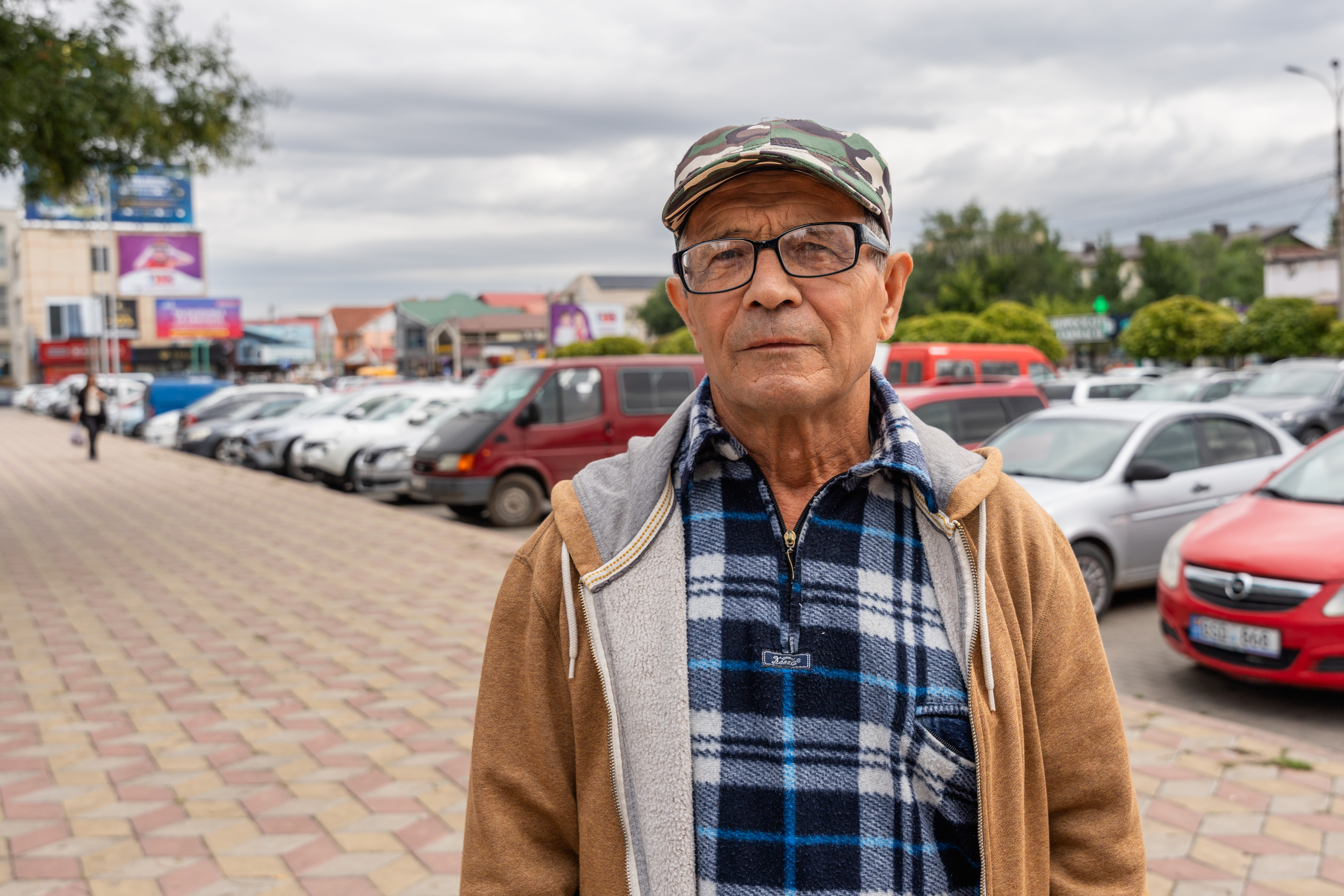 Homme d'un certain âge dans une rue avec des voitures.