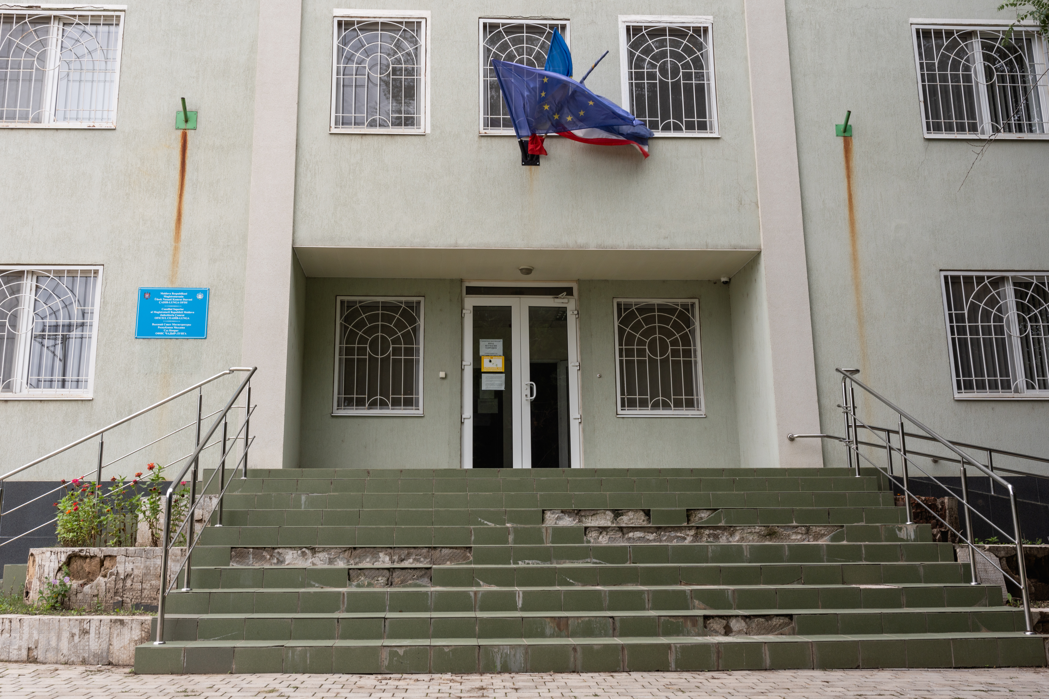 Entrada de um edifício, com a bandeira da UE acima das bandeiras da República da Moldávia e da Gagauzia.