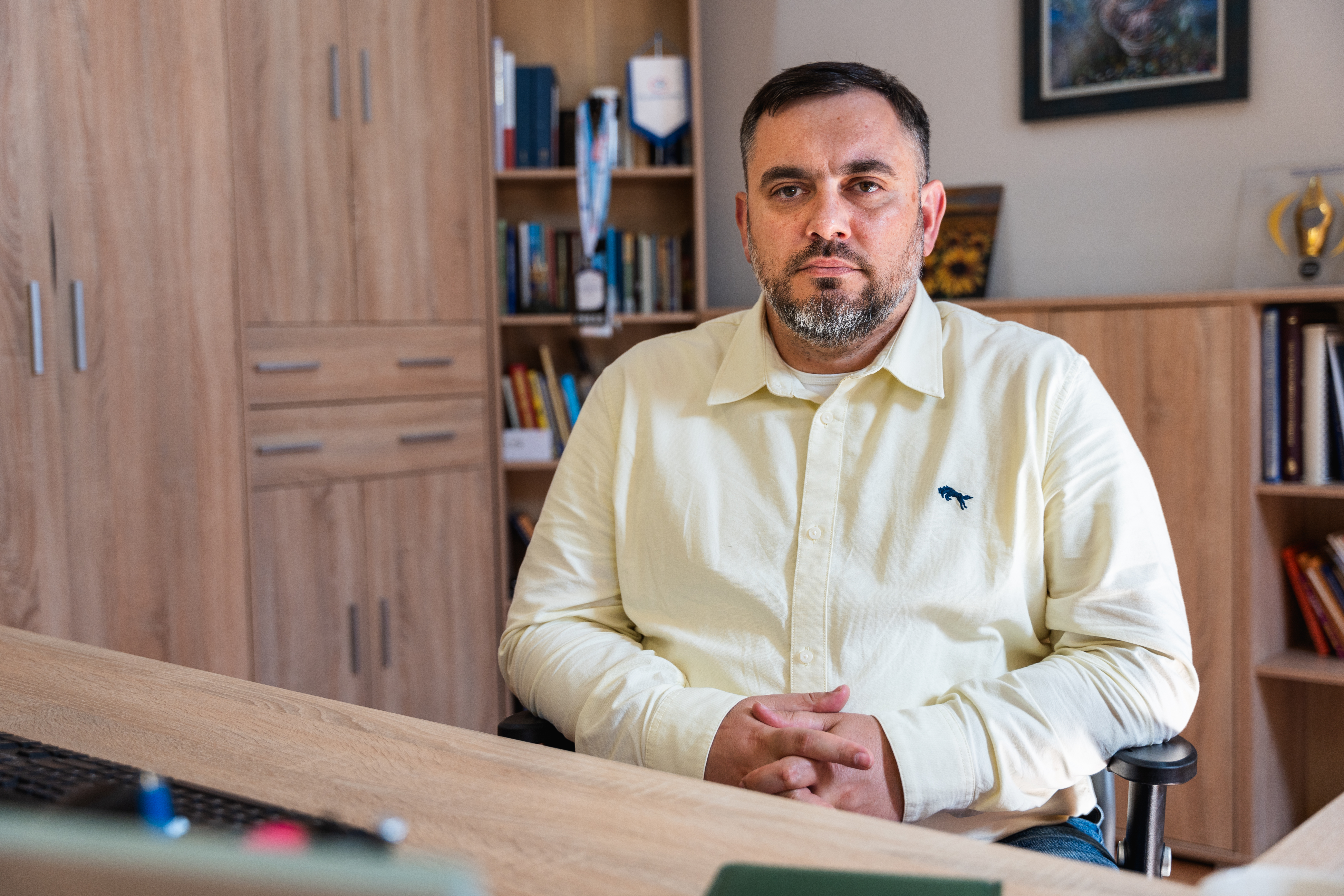 Homme barbu assis derrière son bureau.