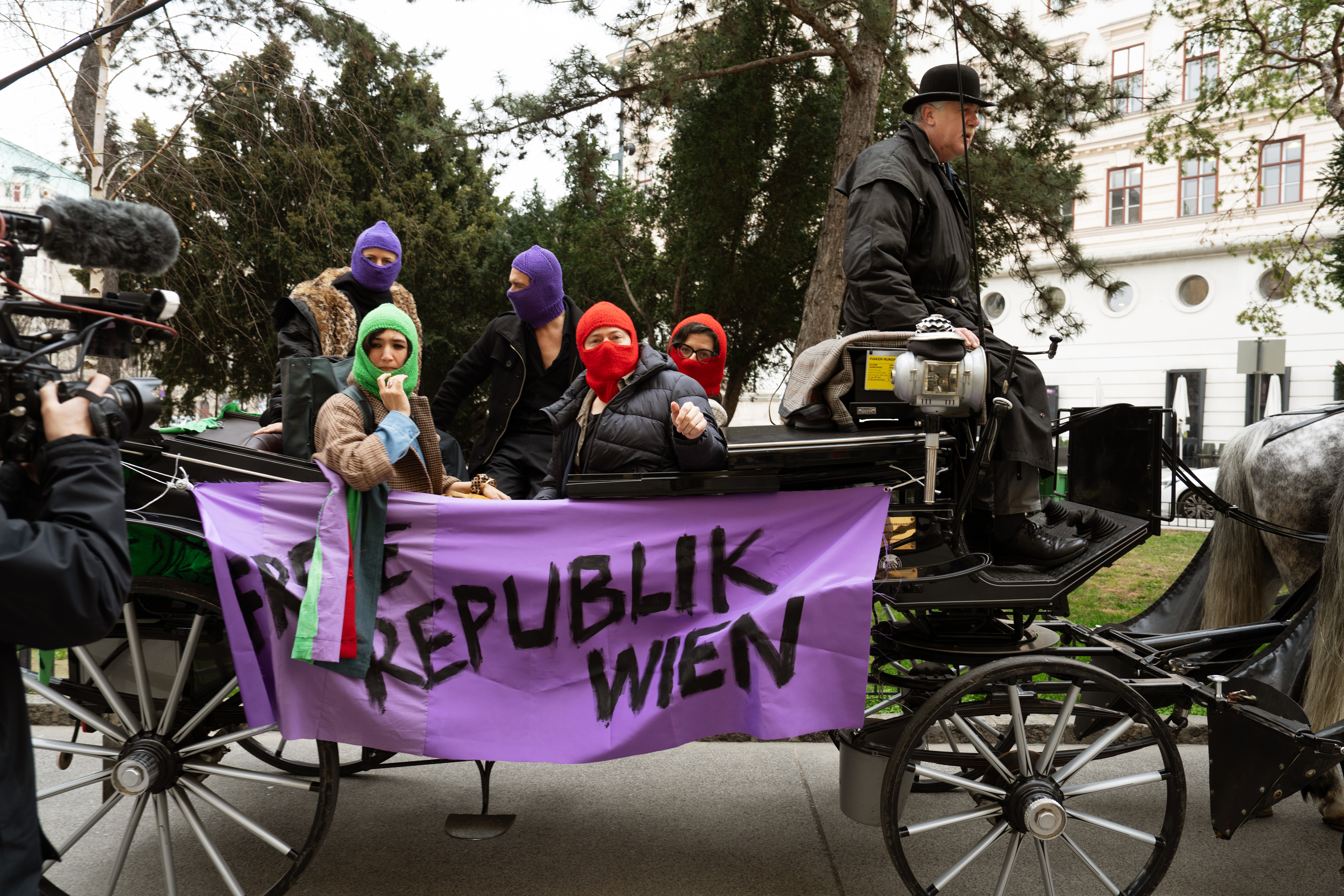 people with colourful balaclavas in old cart