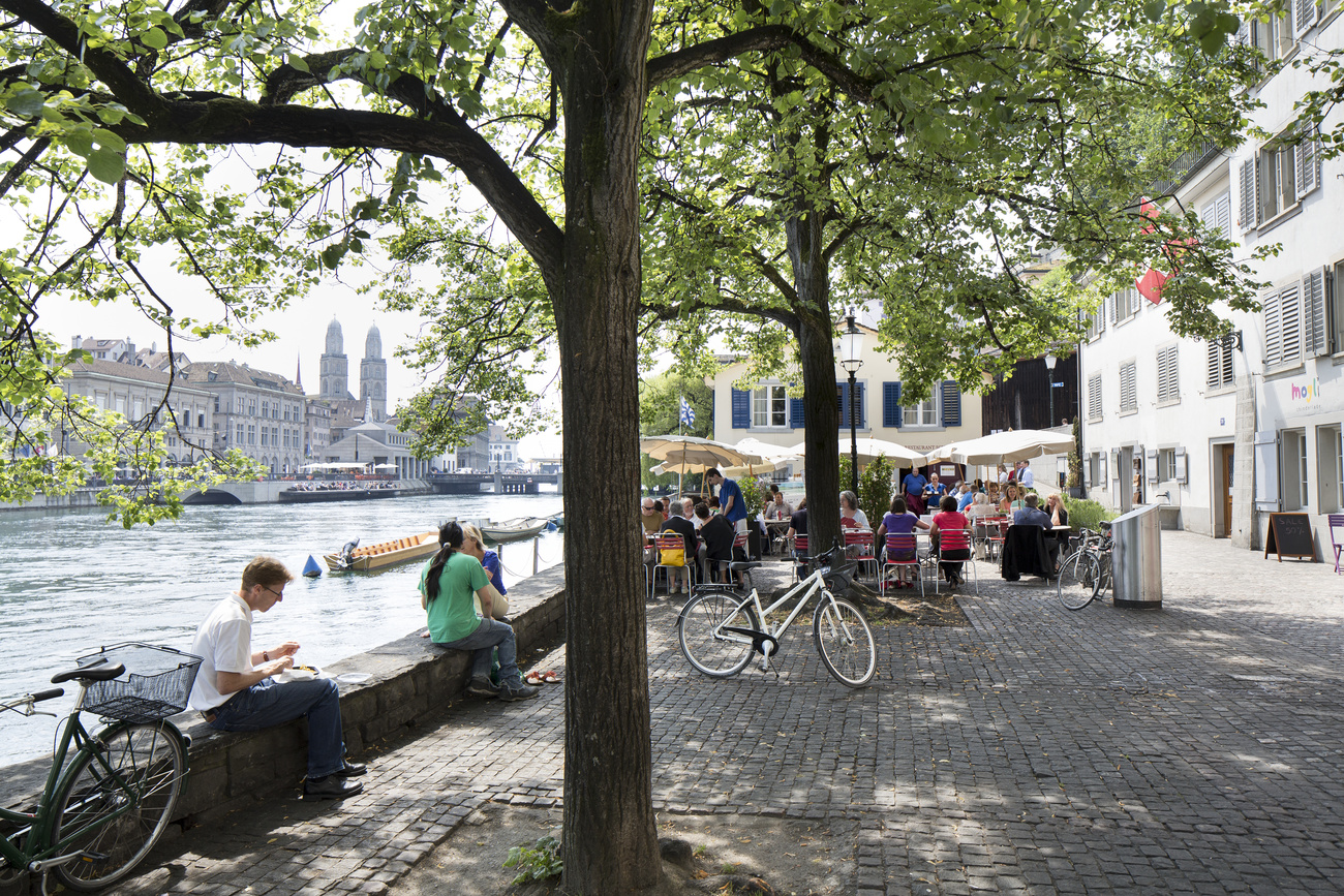 Menschen sitzen am Fluss Limmat in Zürich