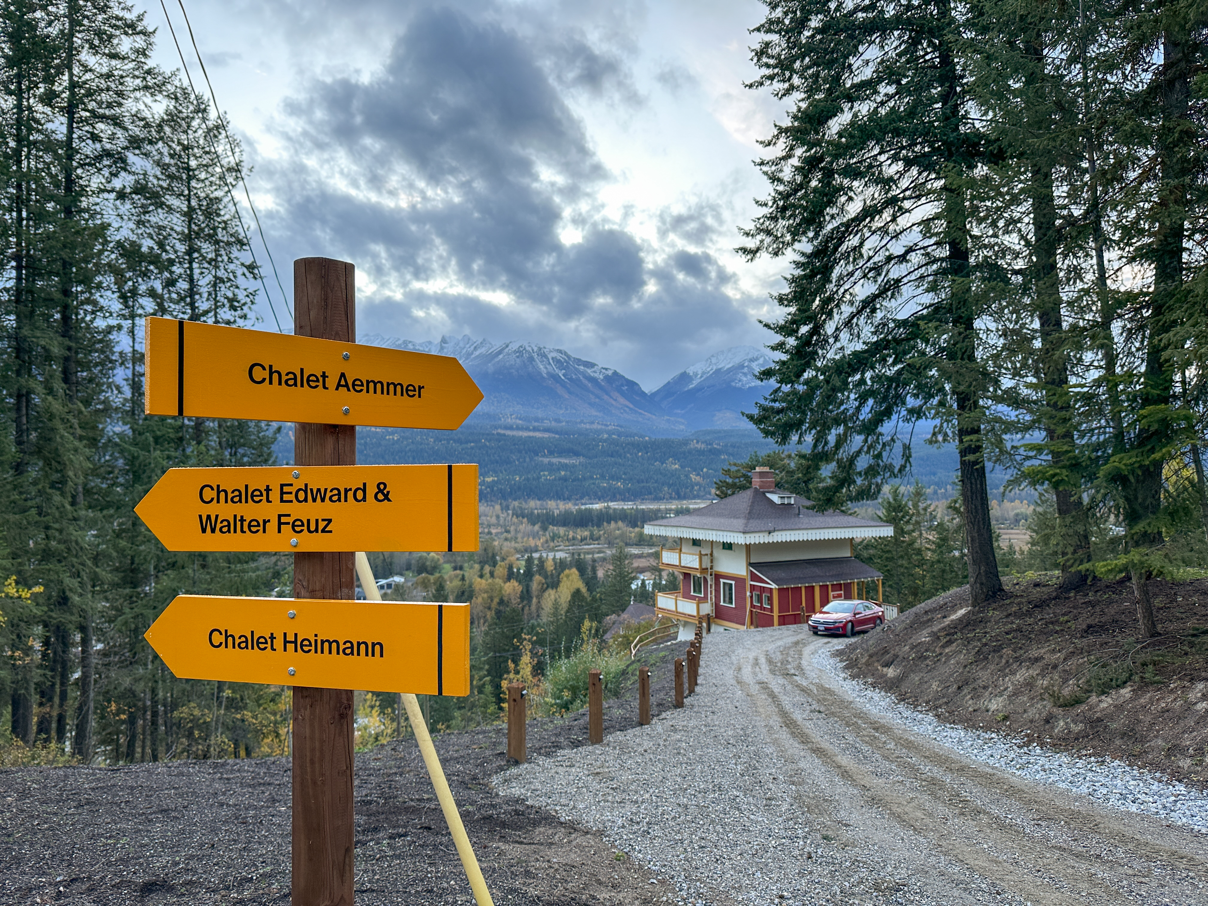 Drei gelbe Wegweise, im Hintergrund ein Chalet