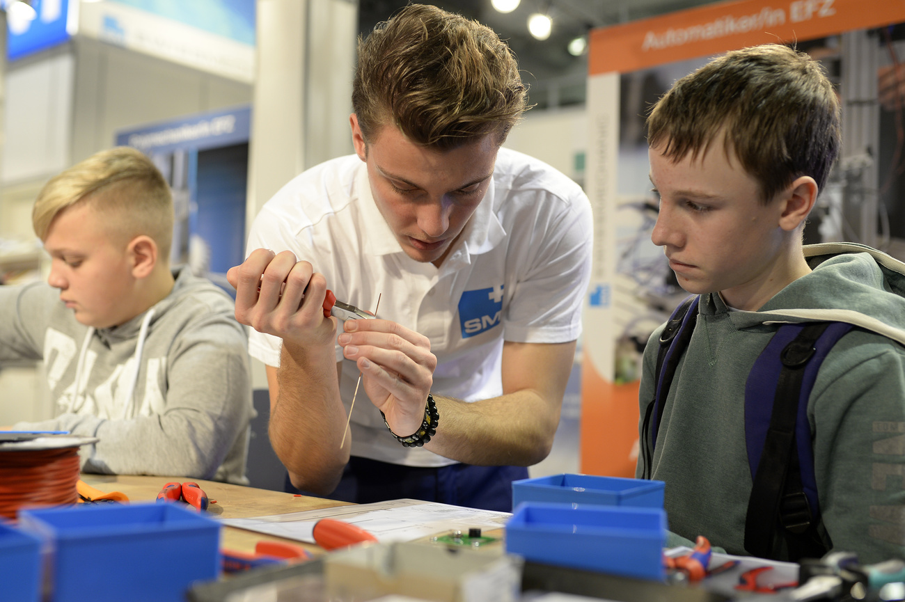 An adult shows youth how to solder metal wires