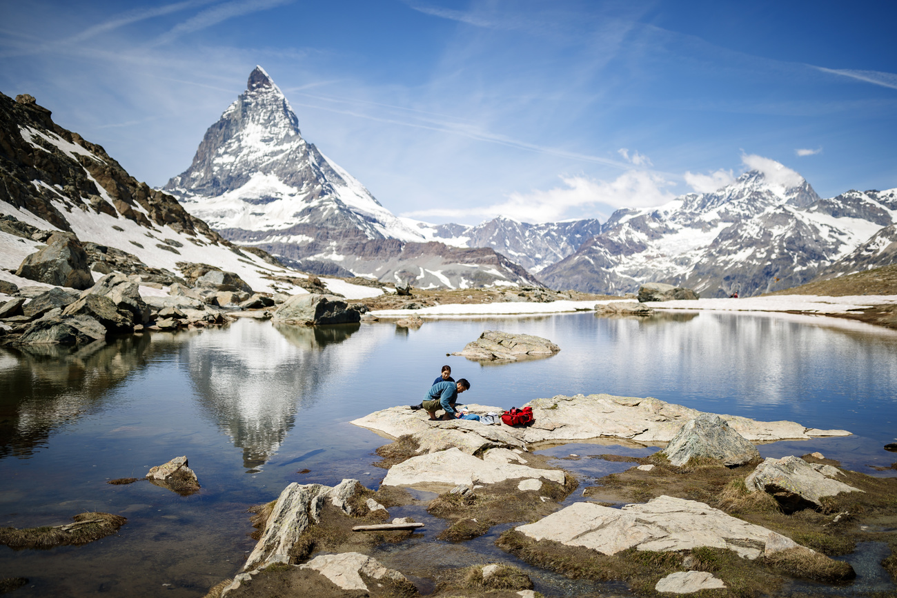 Een foto van enkele toeristen bij een bergmeer met bergen op de achtergrond