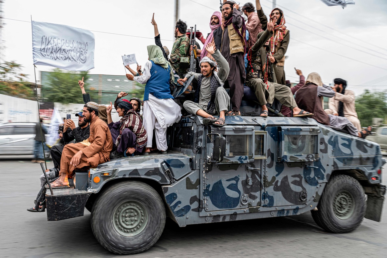 Taliban fighters hold weapons as they ride on a humvee to celebrate their victory day near the US embassy in Kabul on August 15, 2022.