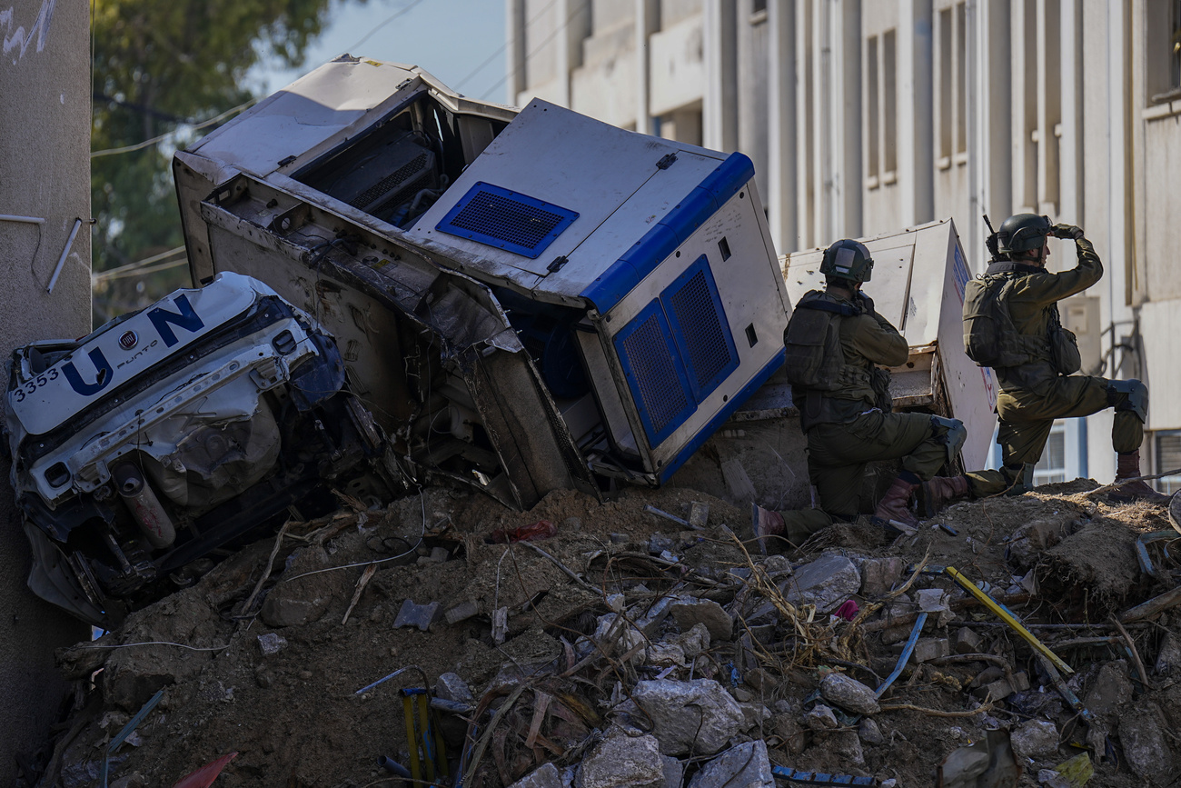 Picture of Israeli soldiers next to crumpled-up UN vehicles in UNRWA compound