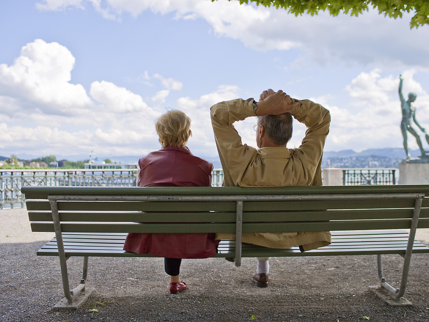 coppia di pensionati su panchina fotografati di spalle