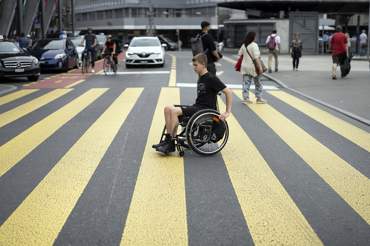 Man on wheelchair on zebra crossing.