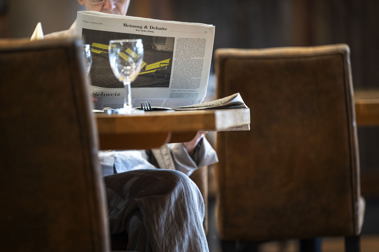 Pessoa lendo jornal em uma mesa