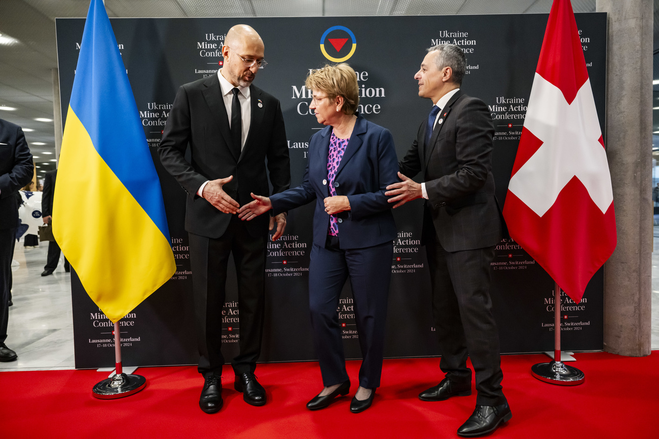 Denys Shmyhal, left, Prime Minister of Ukraines and Viola Amherd, center, President of the Swiss Confederation, shake hands next to Ignazio Cassis, right, Swiss Federal Councilor and Head of the Federal Department of Foreign Affairs during the opening plenary at the Ukraine Mine Action Conference, in Lausanne, Switzerland, Thursday, October 17, 2024.