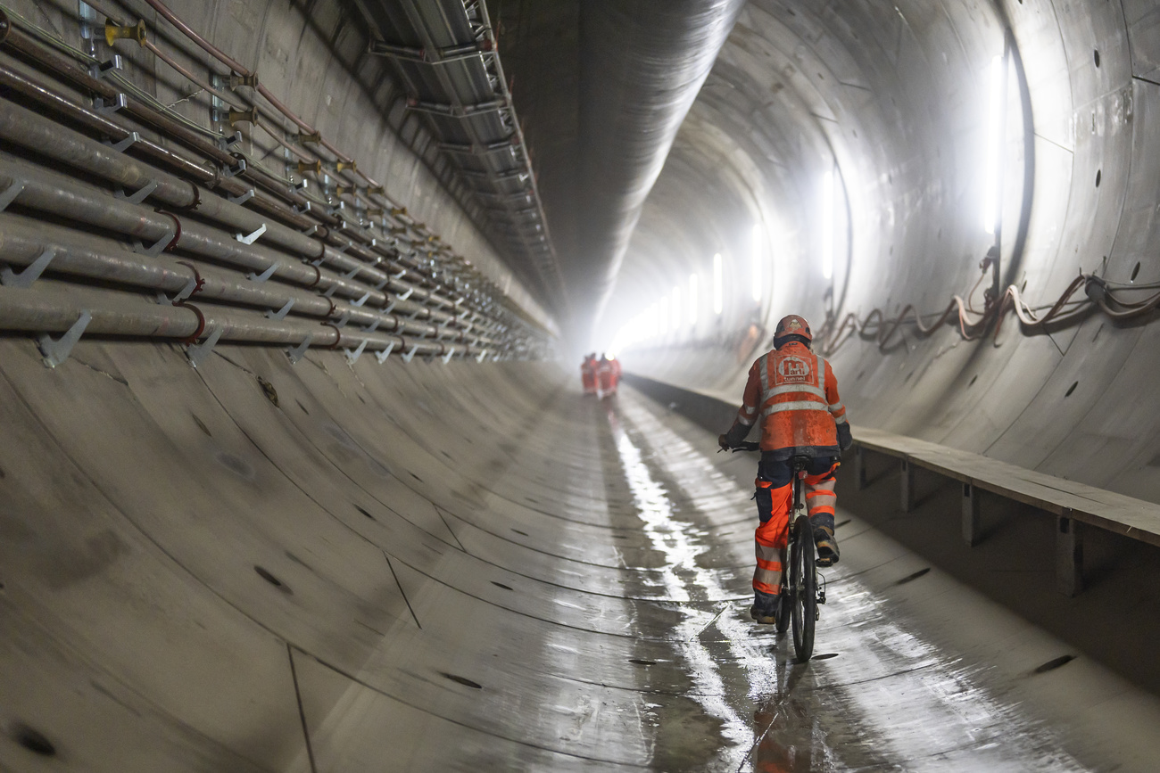 man in bright orange utility wear riding a bike through a large tunnel