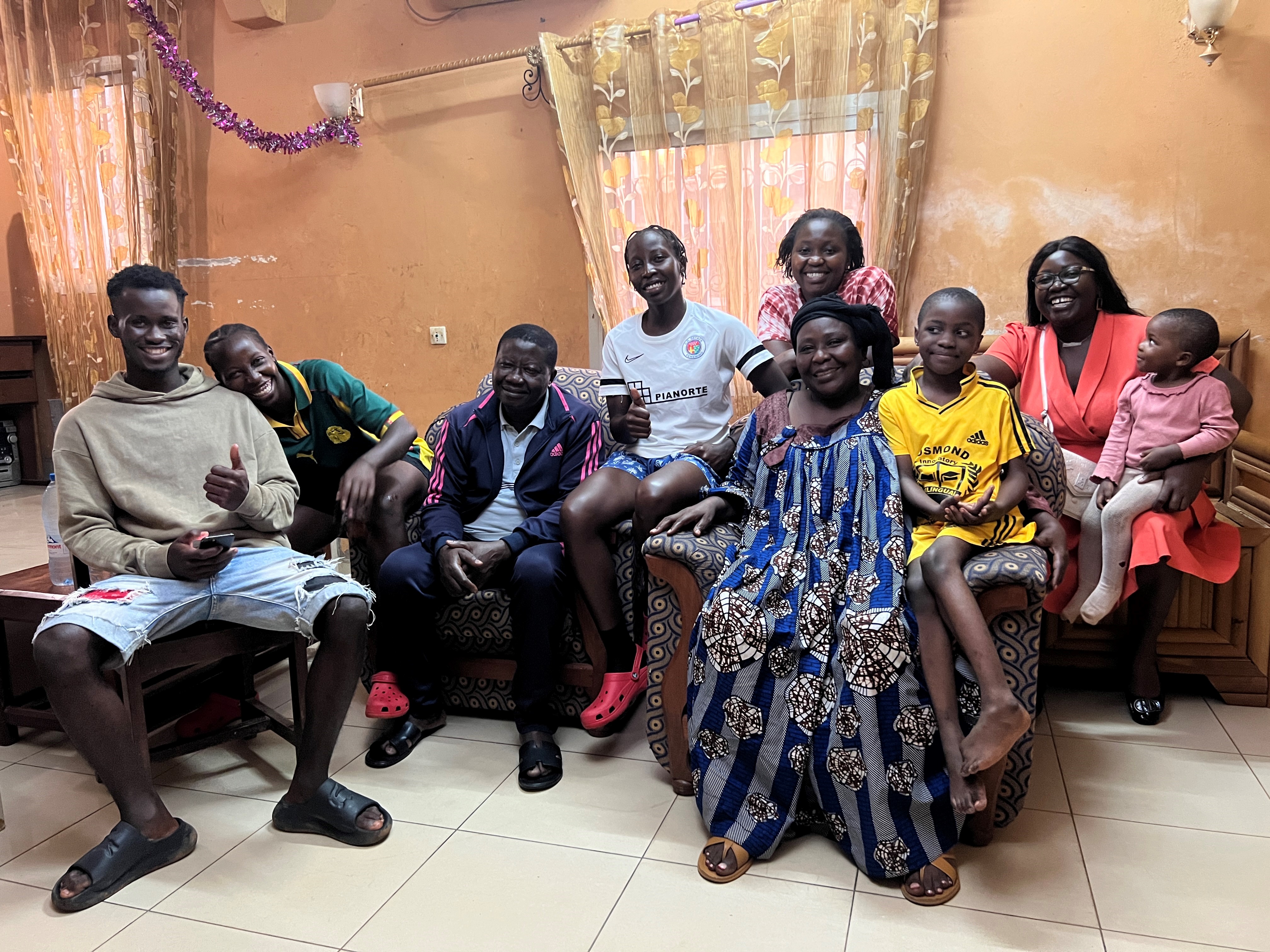 La famille Priso au complet dans sa maison. Les jumelles Pauline Marcelle et Rose Michelle sont en 2e et 4e position depuis la gauche. Les parents sont assis sur les fauteuils au centre de l'image.