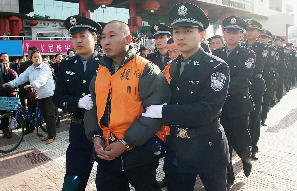 Homme menotté mené à son exécution par des policiers chinois.