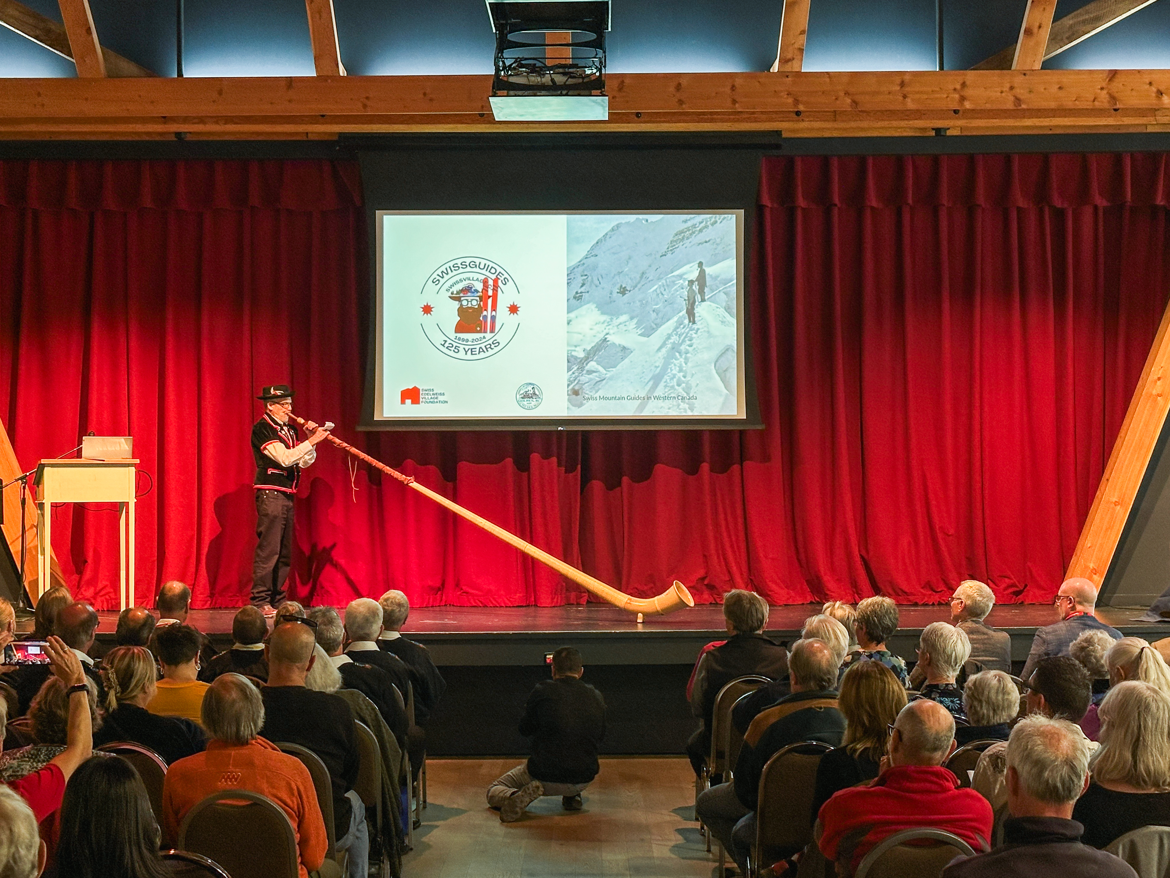 Mann spielt Alphorn auf der Bühne