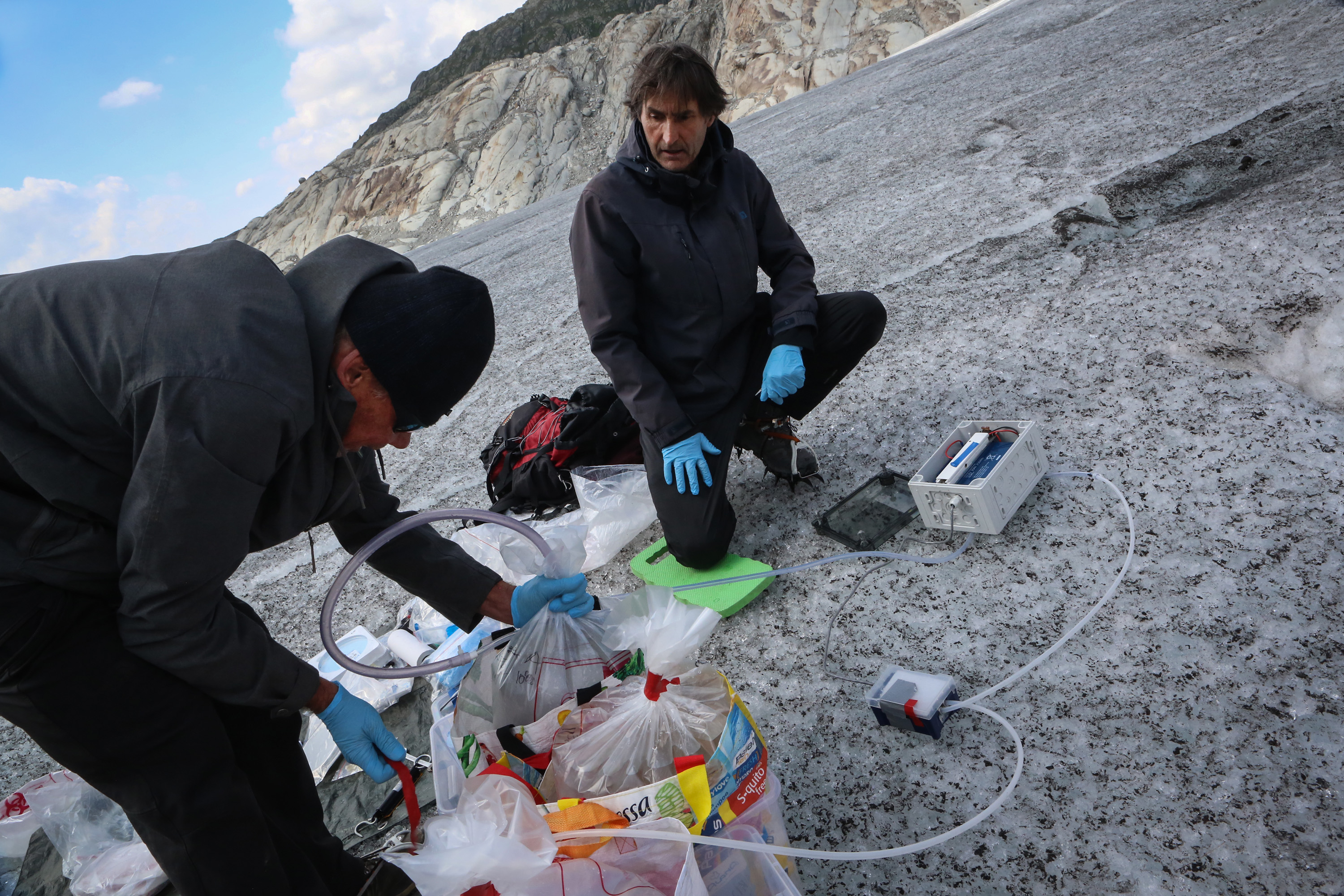 Zwei Männer mit Gletscherwasser in Plastiksäcken.