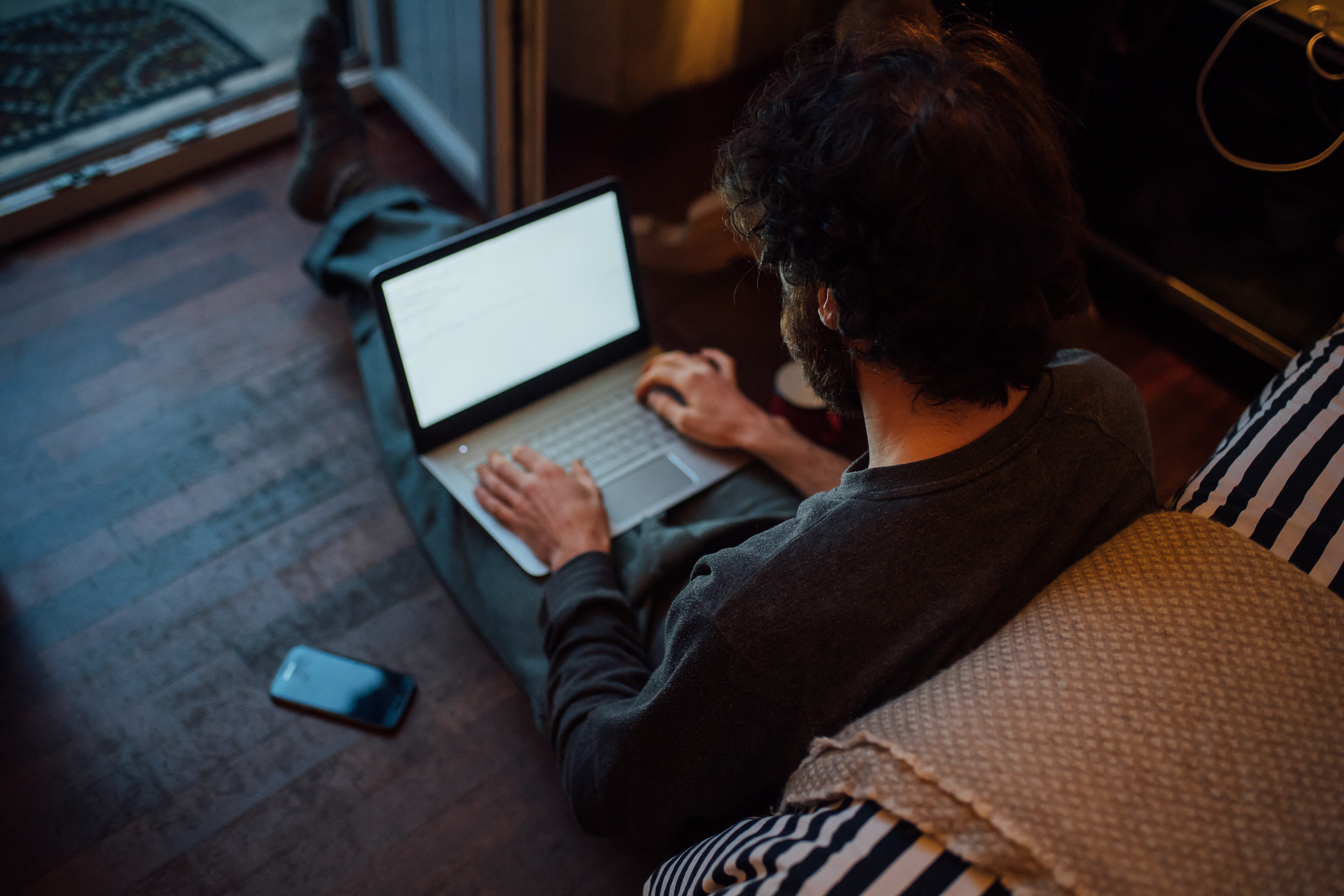 Jeune homme barbu utilisant un ordinateur portable dans sa chambre