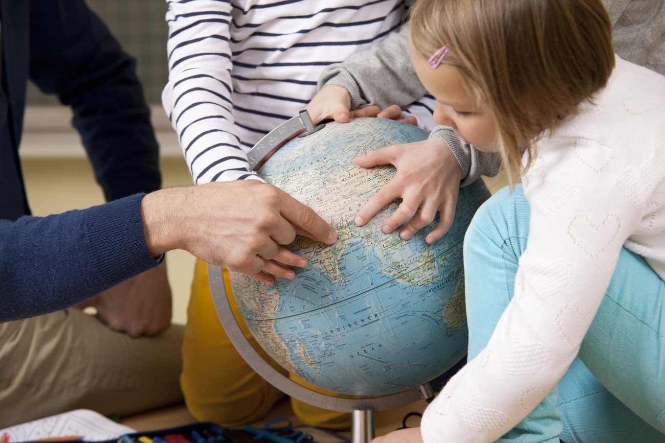 Adulte et enfants pointant le globe