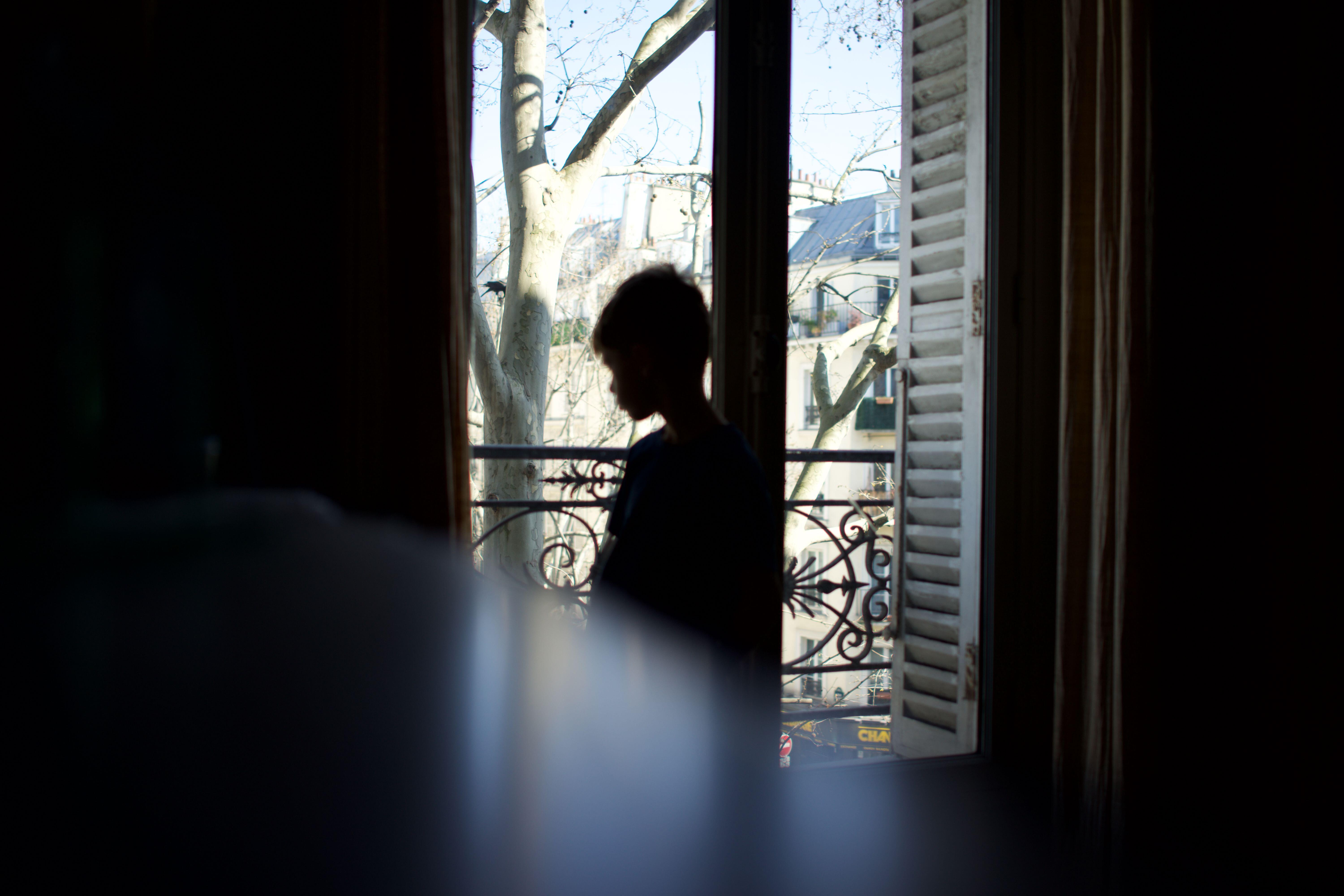 Enfant debout, silhouette, regardant par la fenêtre, de profil, vulnérable, seul