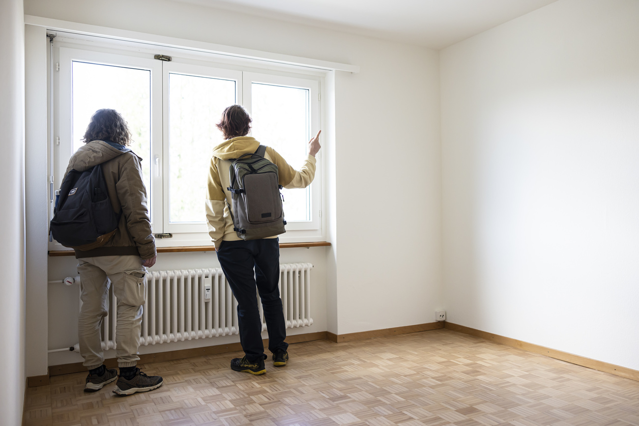 Un couple regardant par la fenêtre d'un appartement vide.