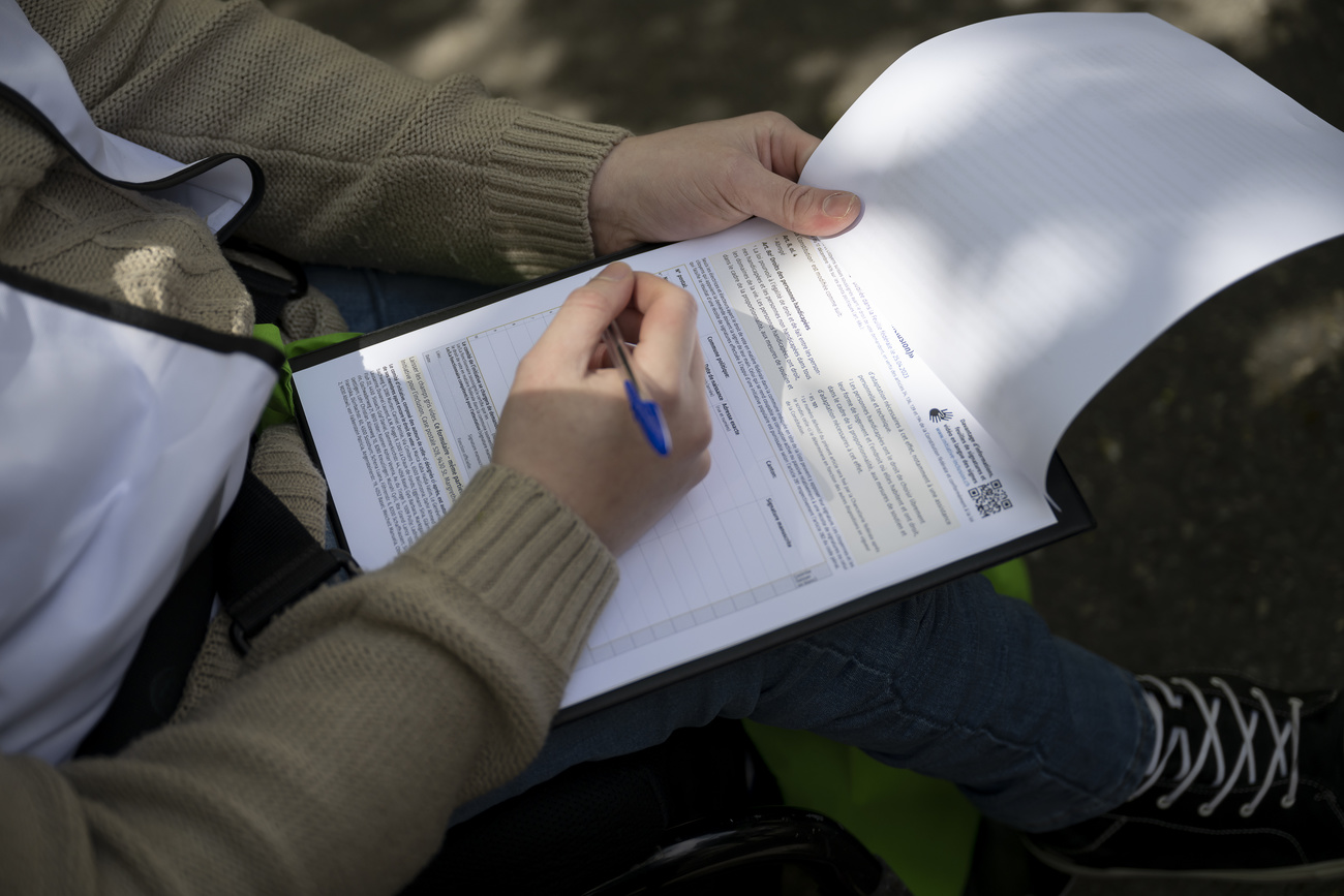 Eine Person unterzeichnet eine Sammelliste an der ersten Sammelaktion kurz vor einer Medienkonferenz zur Lancierung der eidgenoessischen Volksinitiative "Fuer die Gleichstellung von Menschen mit Behinderungen (Inklusions-Initiative)", am Donnerstag, 27. April 2023 in Bern. (KEYSTONE/Anthony Anex)