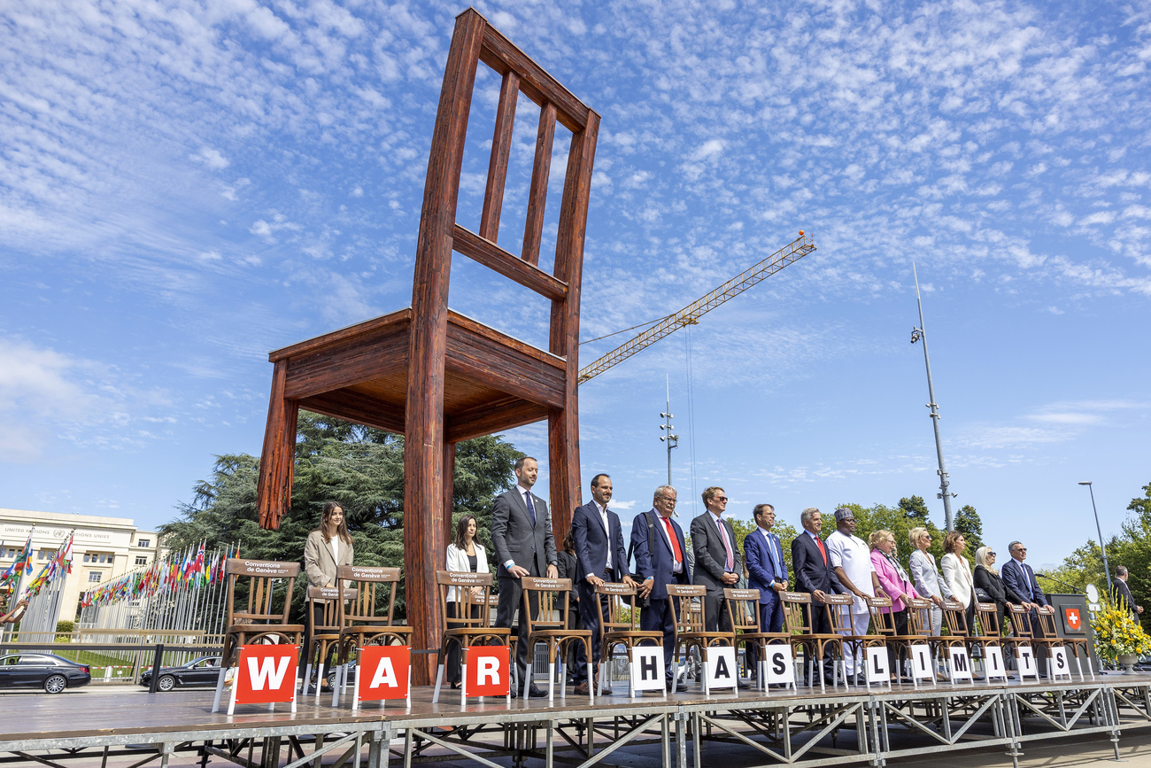 Members of the UN Security Council stand next to each other outside, with a huge chair sculpture in the background