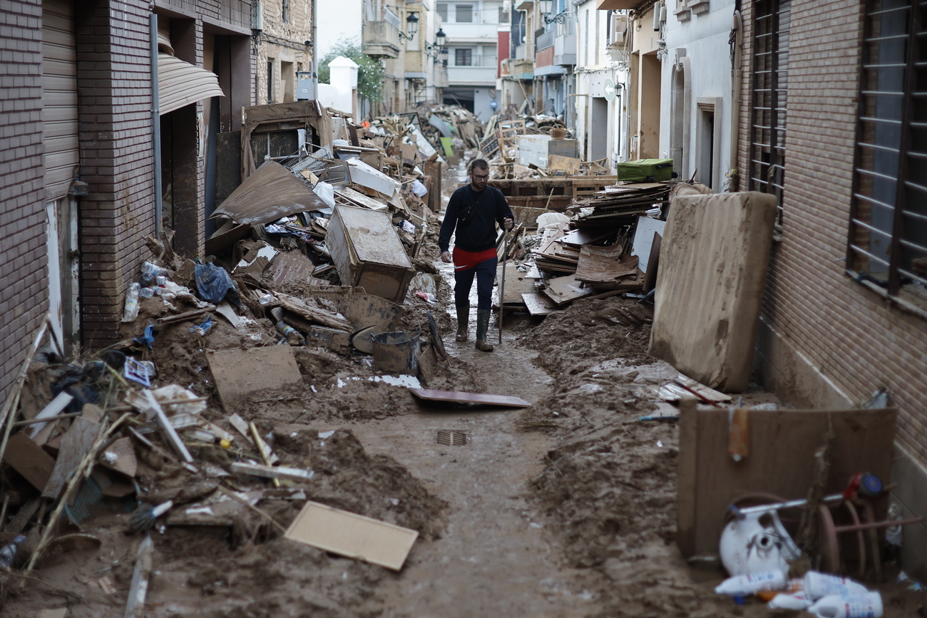 Un hombre camina por una calle cubierta de barro y escombros en la ciudad de Paiporta, Valencia, afectada por las inundaciones.