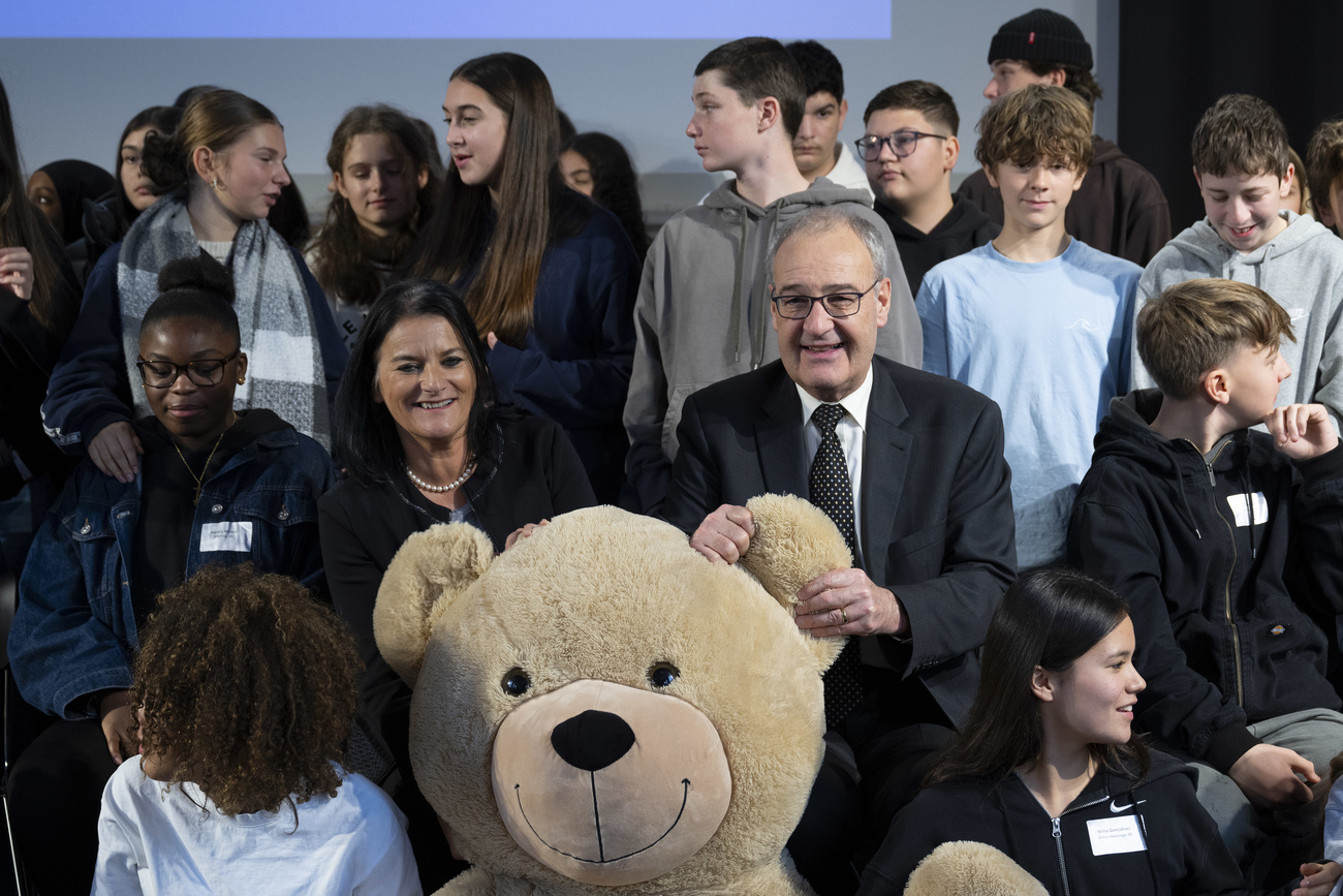 Wirtschaftsministern Guy Parmelin posiert mit Tedd-Bär und Schüler:innen für ein Foto