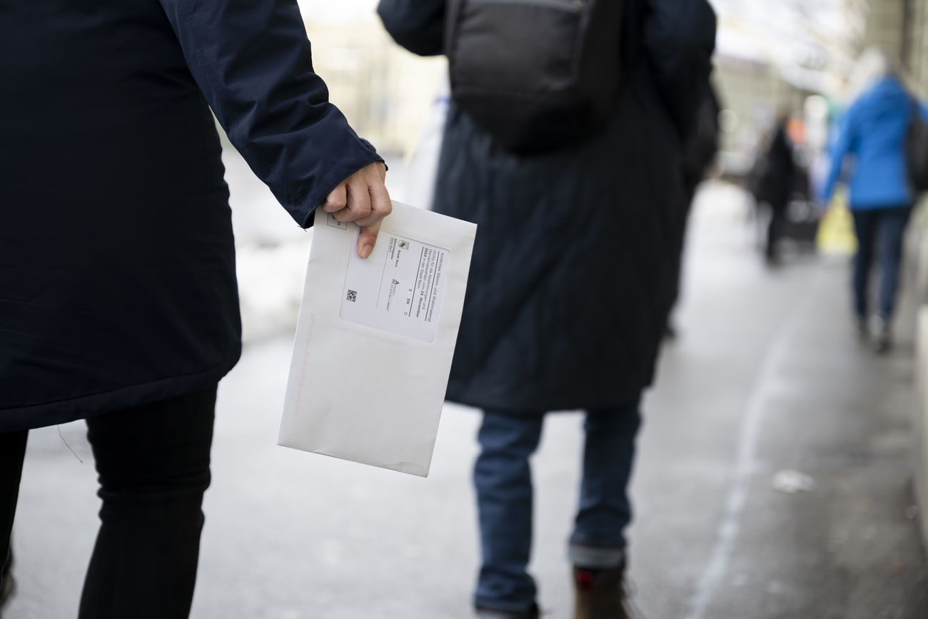 A voter carries his ballot envelope to the polling station on Sunday, 24 November 2024, in Bern. The Swiss electorate votes on four proposals. (KEYSTONE/Anthony Anex).