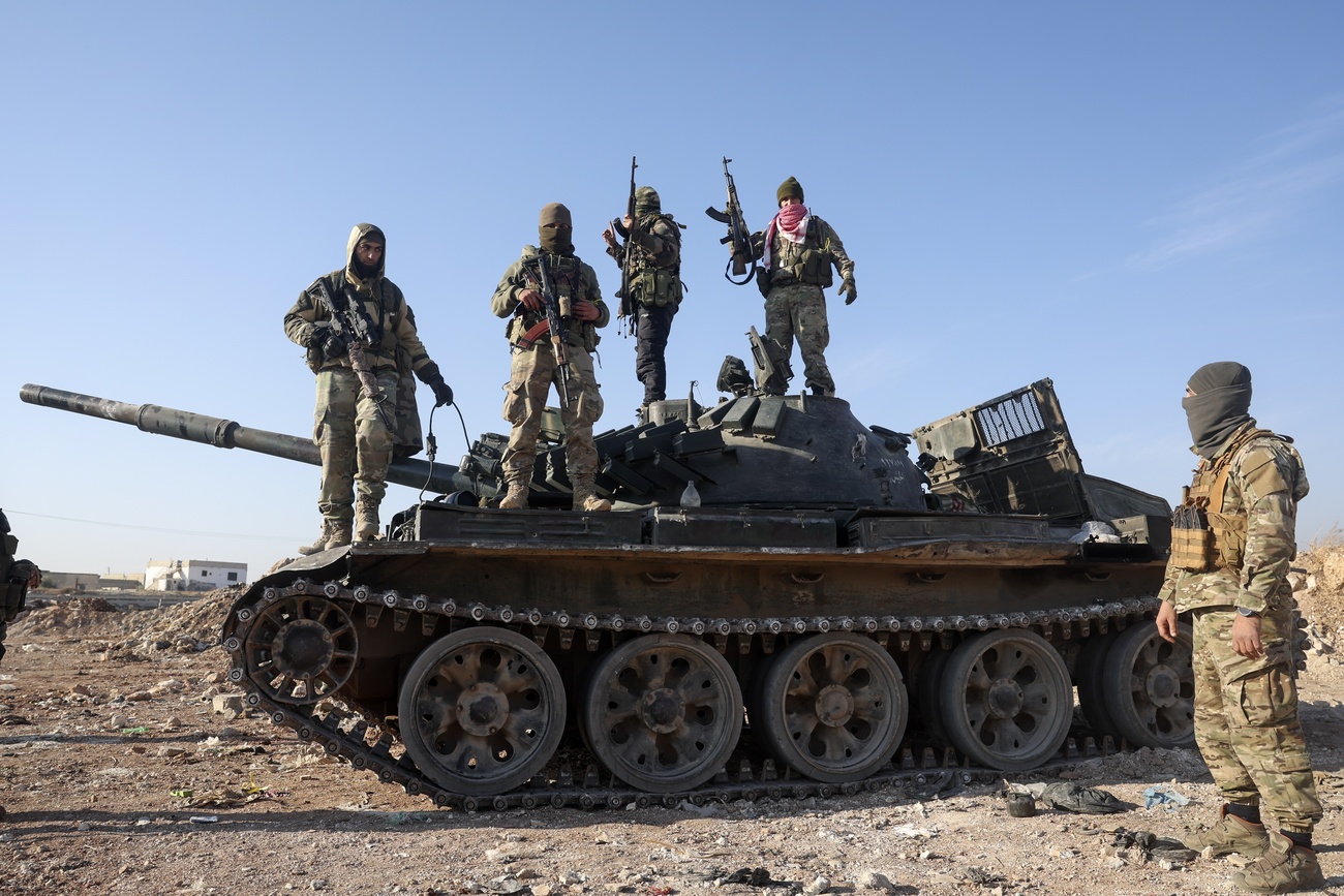 Syrian opposition fighters stand on a seized Syrian army armoured vehicle on the outskirts of Hama, Syria, 3, December 2024.