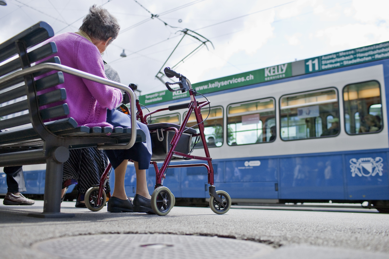 An elderly woman sits with her walking aid on a bench in Paradeplatz square in Zurich, Switzerland