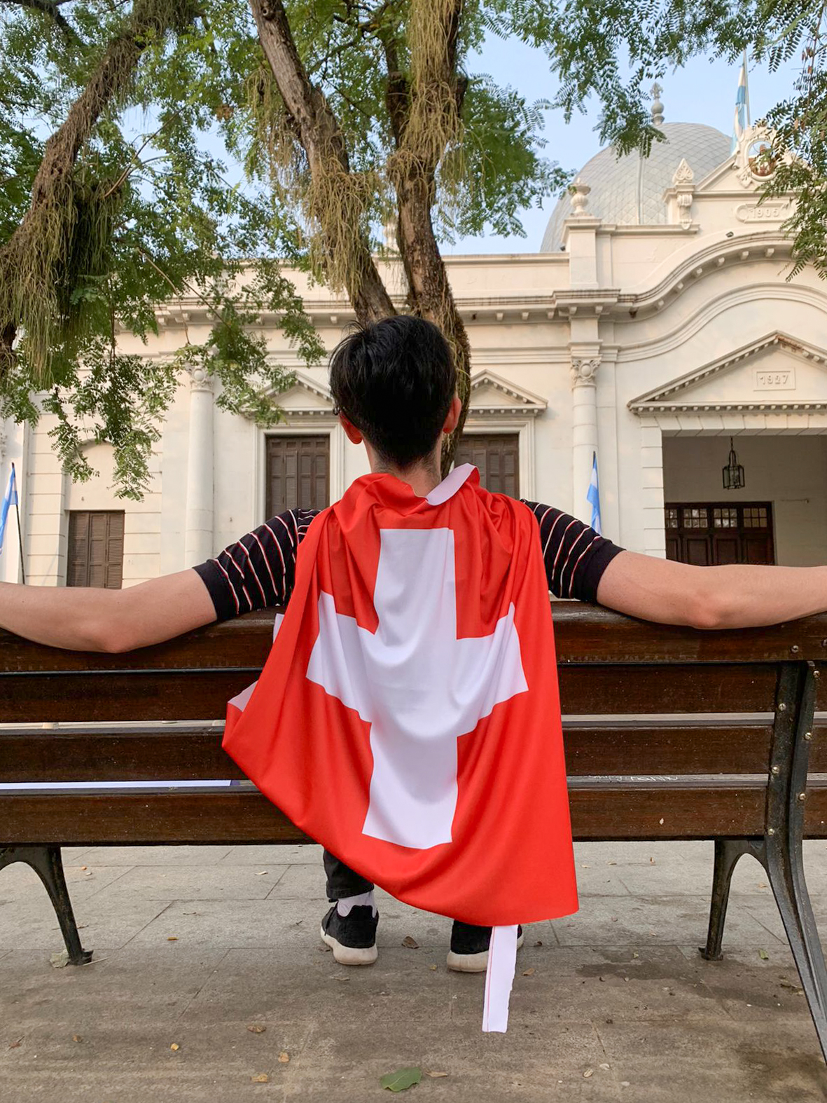 Jovem de costas com a bandeira suíça pendurada nele