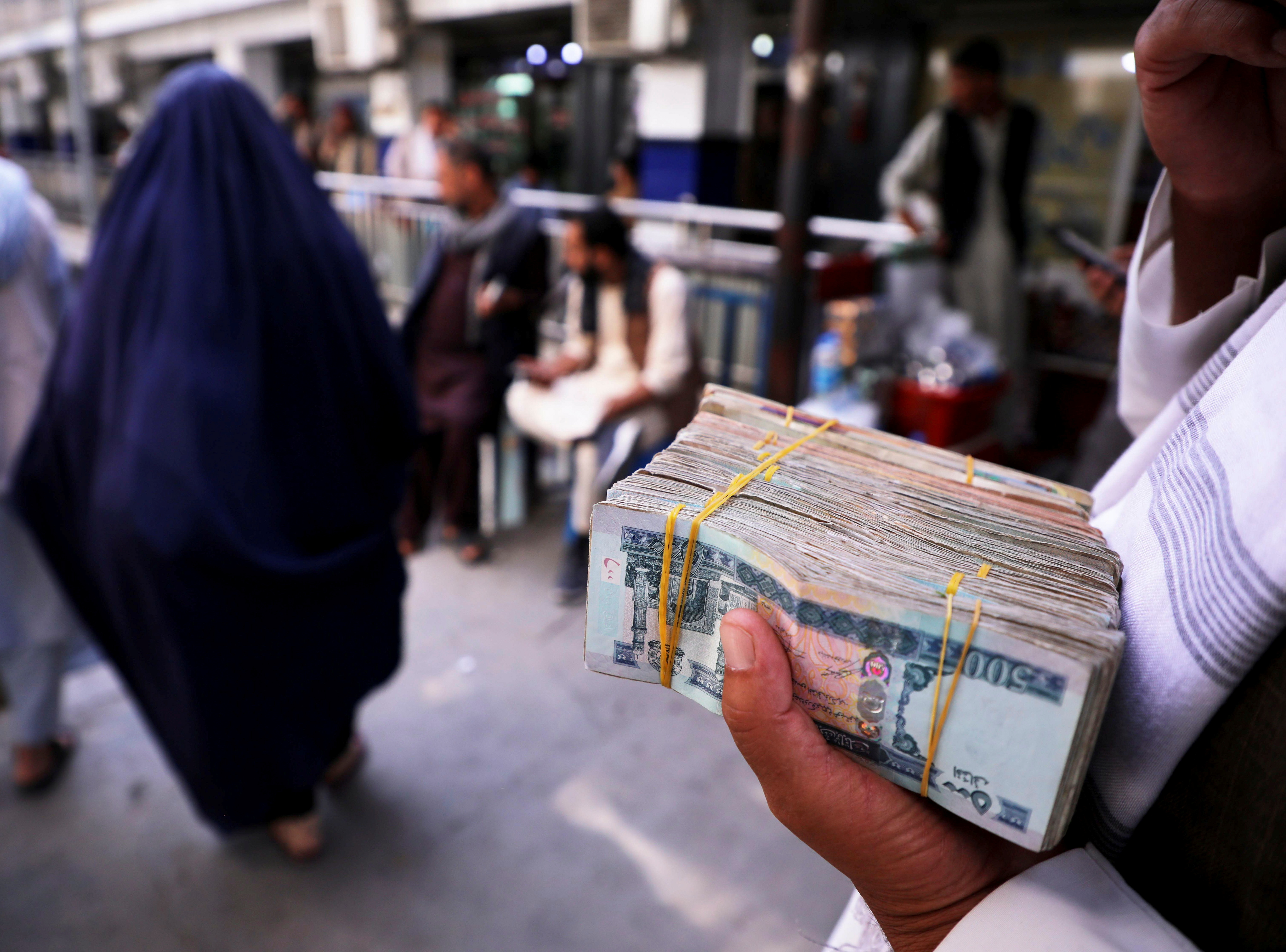 A person holds a bundle of Afghan afghani banknotes at a money exchange market, following banks and markets reopening after the Taliban took over in Kabul, Afghanistan, September 4, 2021. REUTERS/Stringer