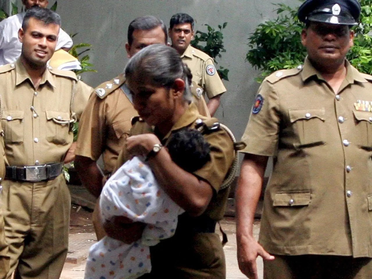 Eine Polizistin bringt in Sri Lanka ein Baby in Sicherheit.