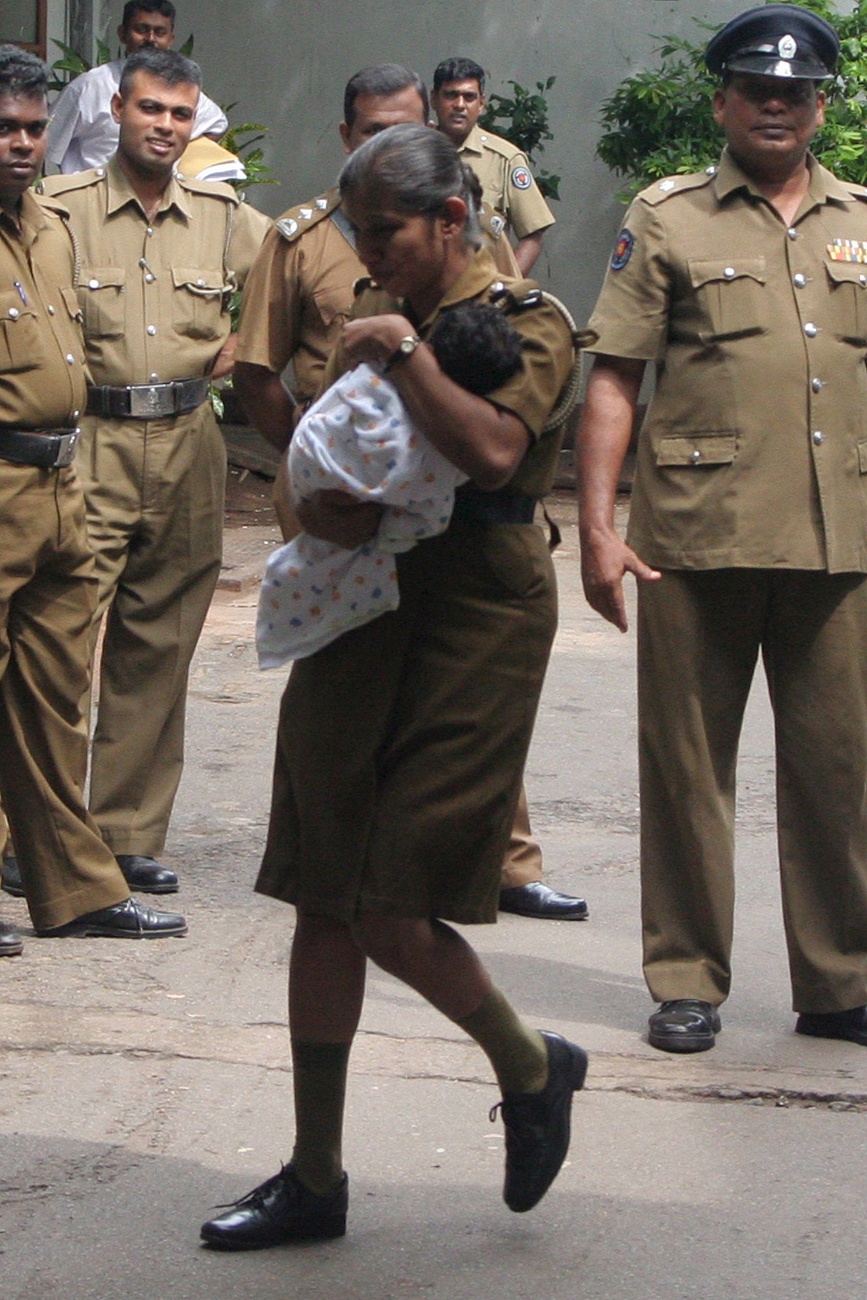 Polizistin in Sri Lanka trägt ein Baby, dessen Adoption an ein europäisches Paar gegen das Gesetz verstossen hätte