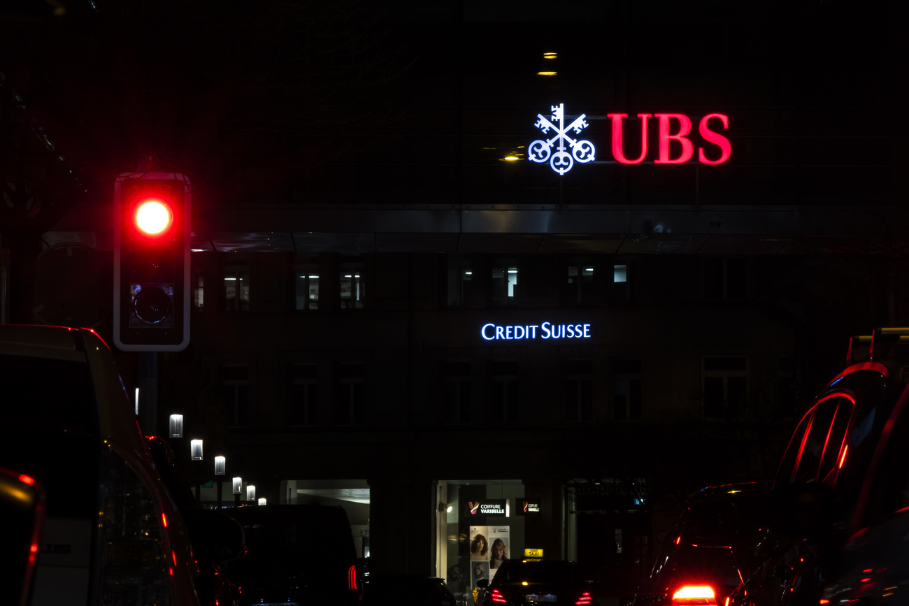 Die beleuchteten Logos der Schweizer Banken Credit Suisse und UBS sind am Samstag, den 18. März 2023, neben Ampeln auf Gebäuden in Zürich, Schweiz zu sehen.