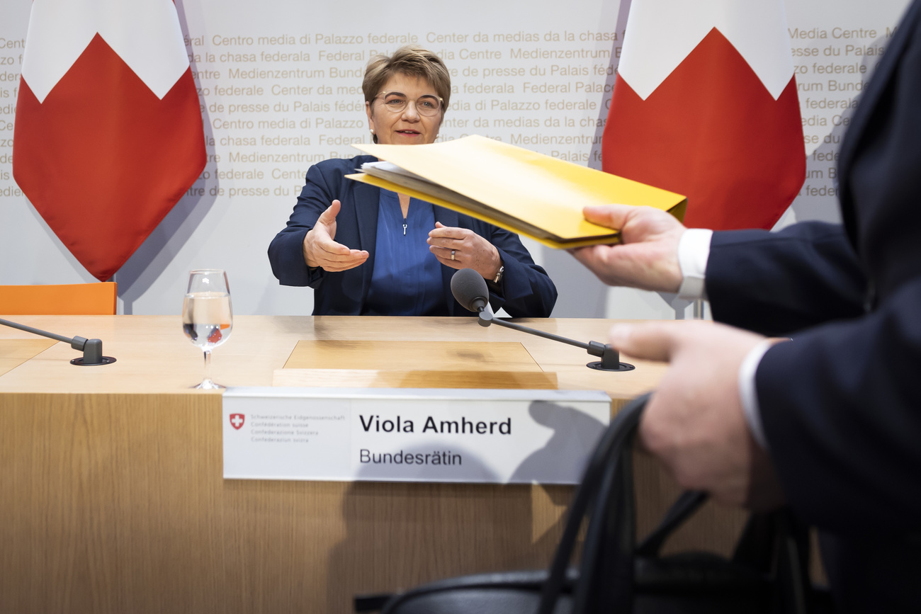 Photo of a woman at a press conference being handed some documents