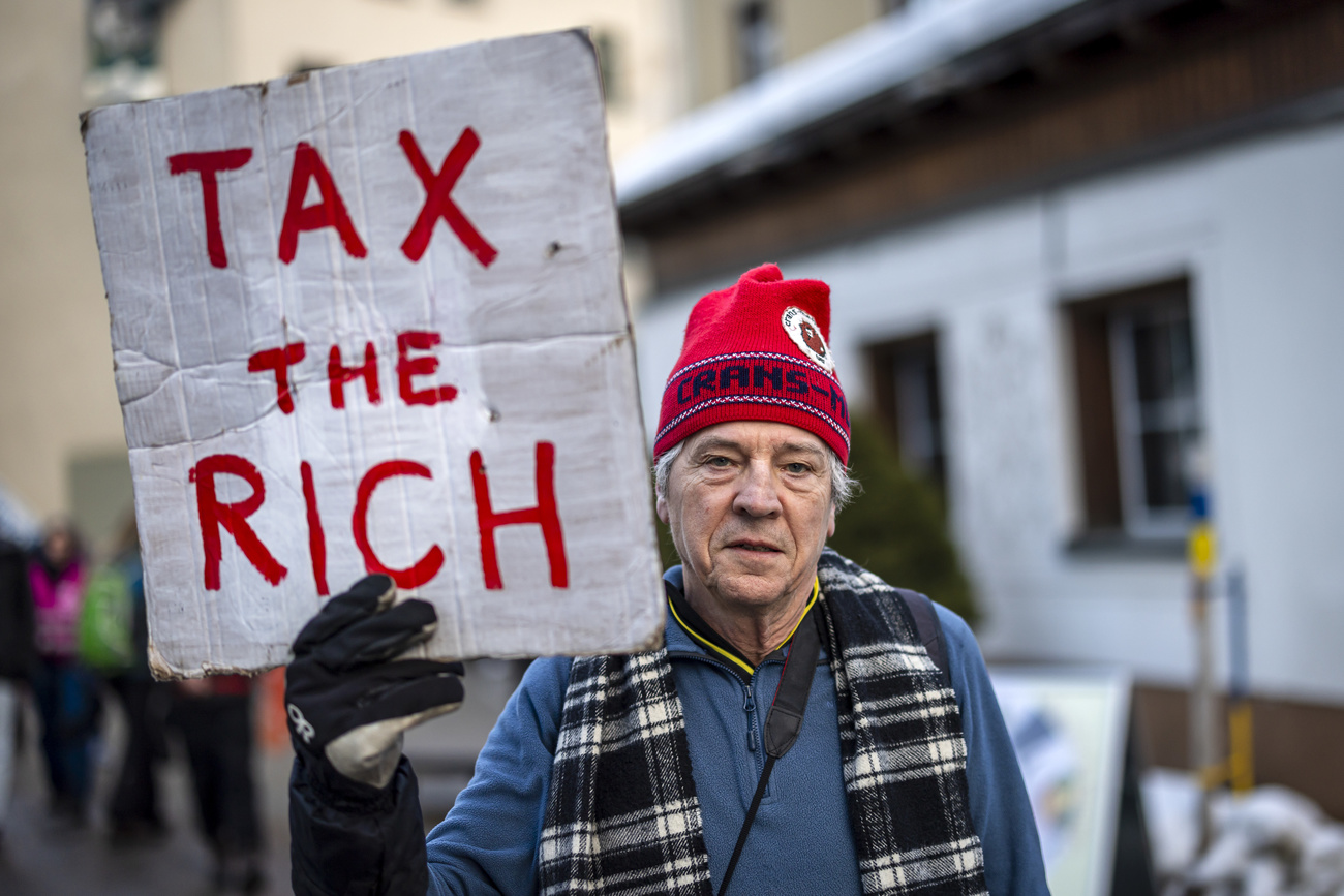 Phil White of Patriotic Millionaires holds a placard reading "Tax the rich" as he attends a demonstration before the annual meeting of the World Economic Forum, WEF, in Davos, Switzerland, on Sunday January 19, 2025. The World Economic Forum annual meeting brings together entrepreneurs, scientists, corporate and political leaders in Davos and takes place from January 20 to 24 in Davos. (KEYSTONE/Michael Buholzer)