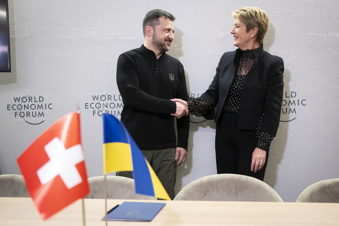 Picture of Volodymy Zelensky and Karin Keller-Sutter shaking hands in front of a table with Swiss and Ukrainian flags