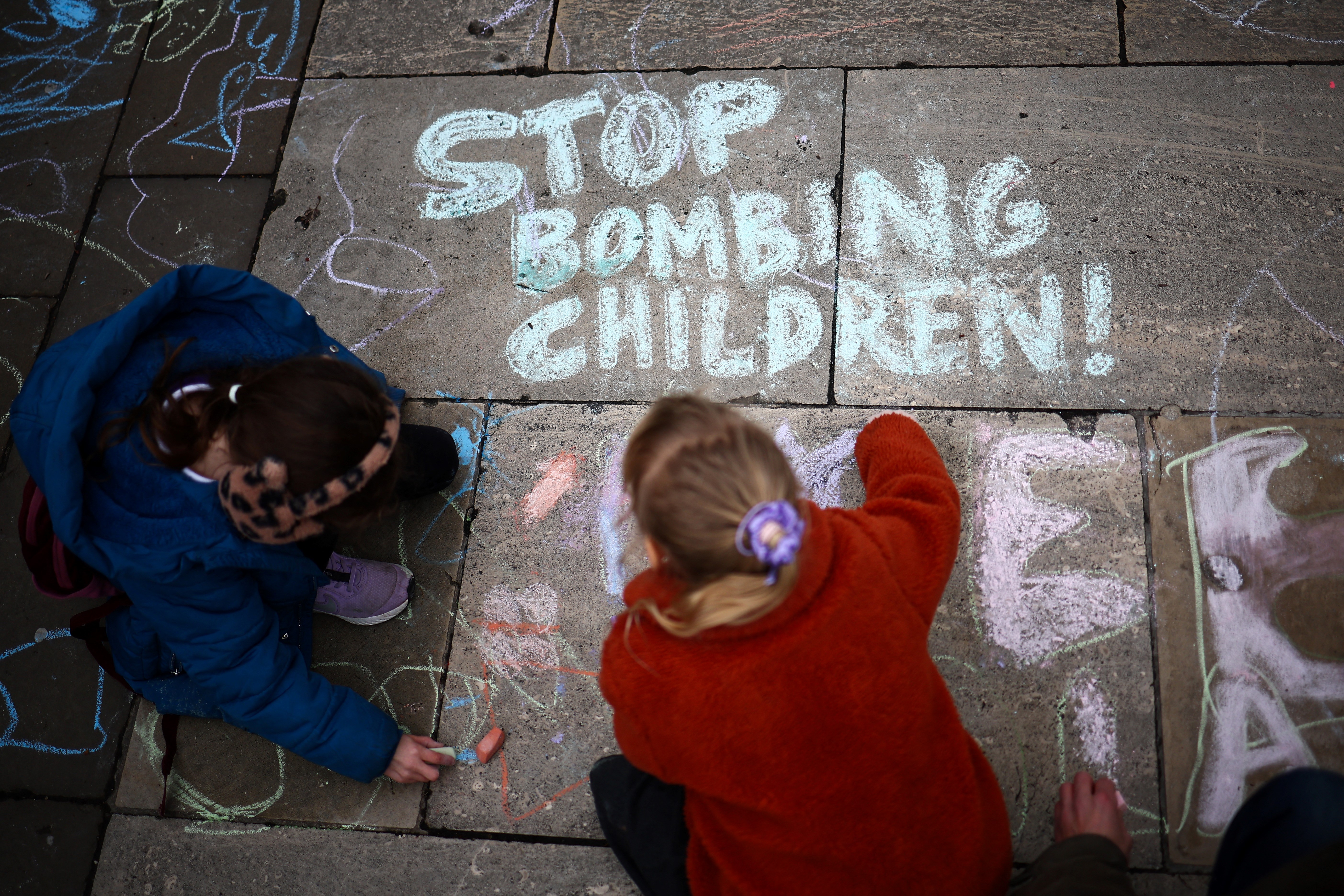 Children write on the floor with coloured piece of chalk "Stop Bombing Children" during a Pro-Palestinian rally in Parliament Square, central London, on February 7, 2024 and called by British associations Stop the War Coalition (StWC) and Campaign for Nuclear Disarmament (CND).