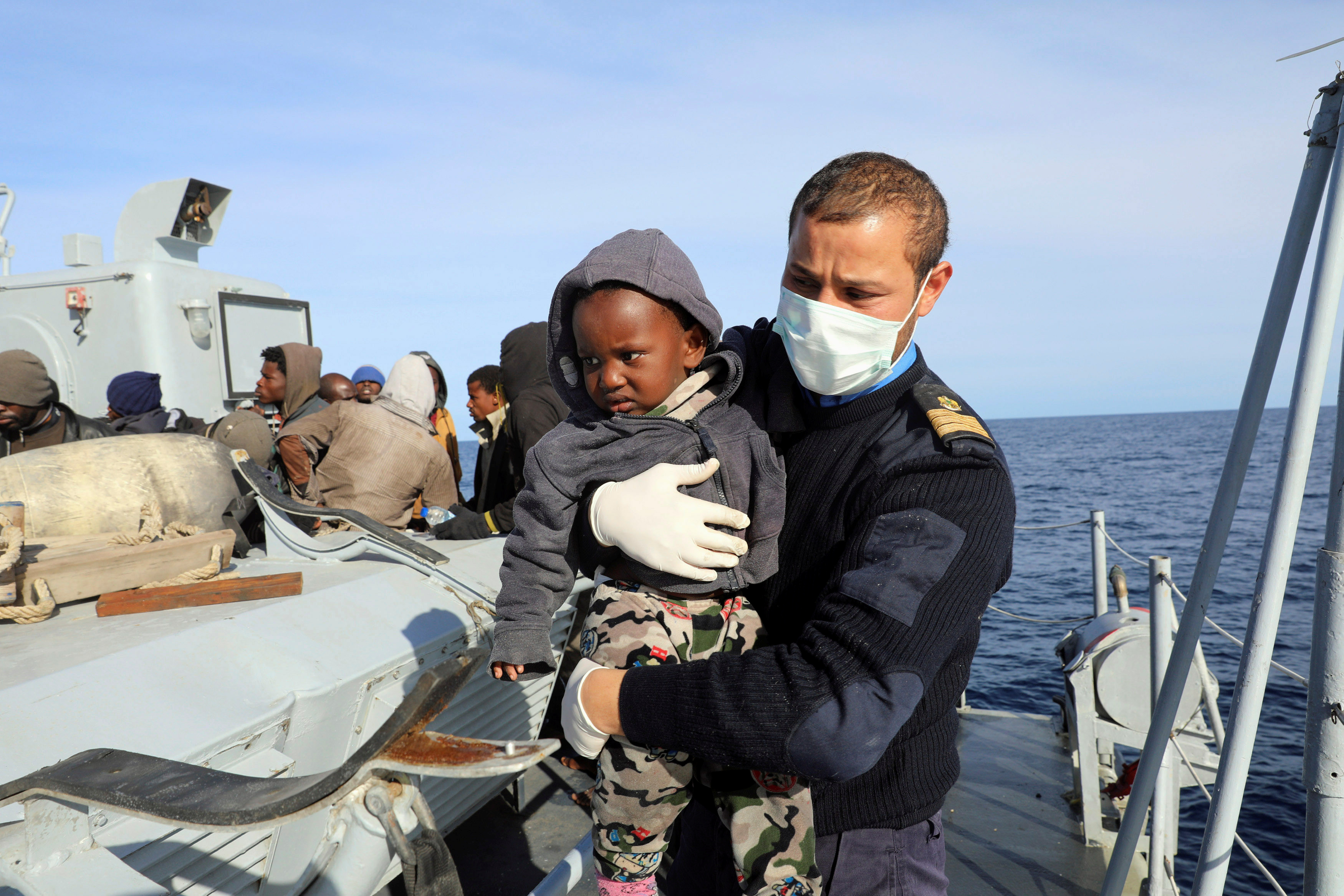 A migrant child is carried while being rescued by Libyan coast guards in the Mediterranean Sea off the coast of Libya.