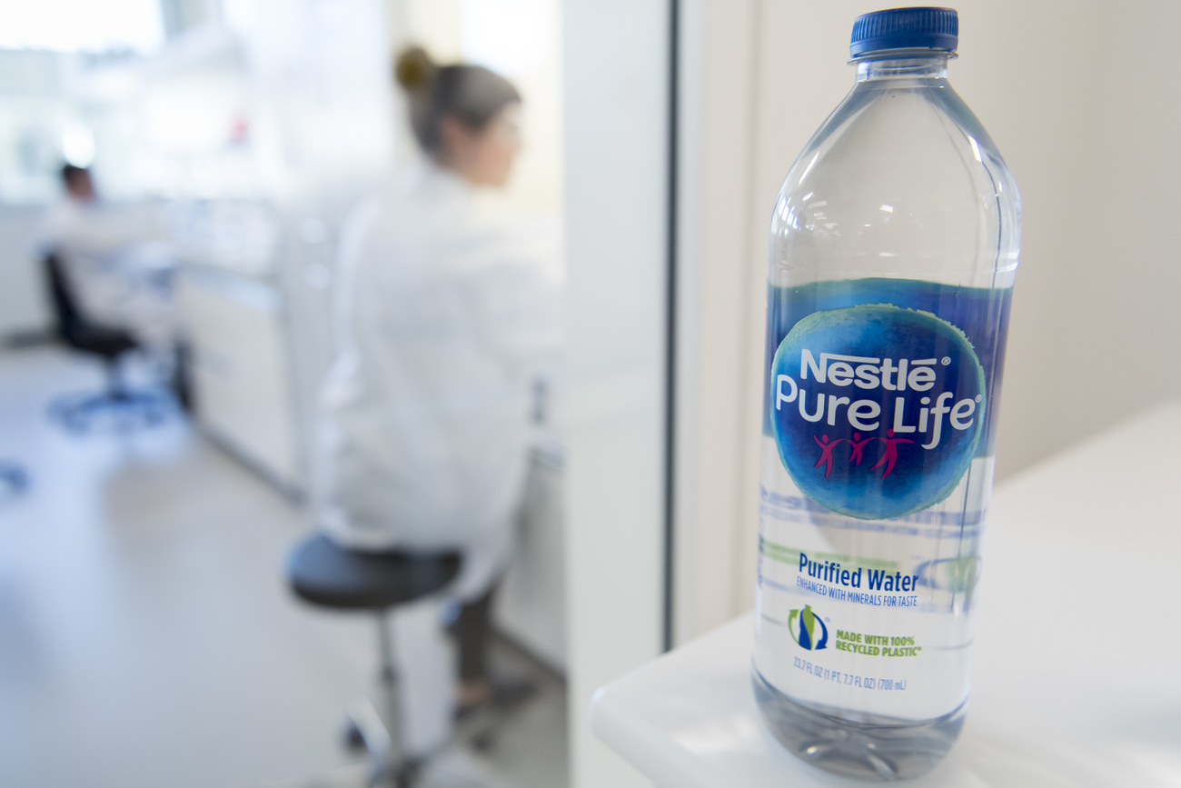 A prototype of a water bottle made out of recycled plastic is pictured in front of staff working in a laboratory during the inauguration of Nestle Institute of Packaging Sciences at the Nestle Research center of the food and drinks giant, in Vers-chez-les-Blanc, Lausanne, Switzerland, Thursday, September 12, 2019. (KEYSTONE/Laurent Gillieron)