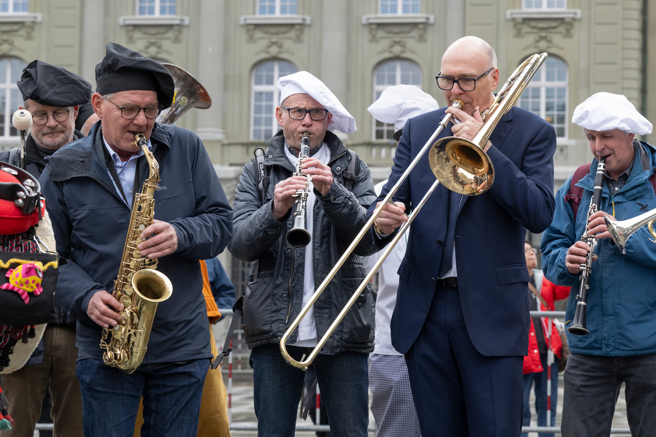 Martin Pfister jouant du trombone devant le Palais fédéral.