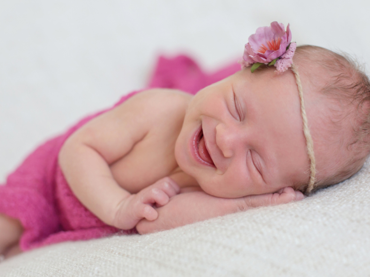 neonata sorridente con fiore rosa in testa