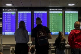 Leute am Flughafen überprüfen Abflug- und Ankunftstafeln